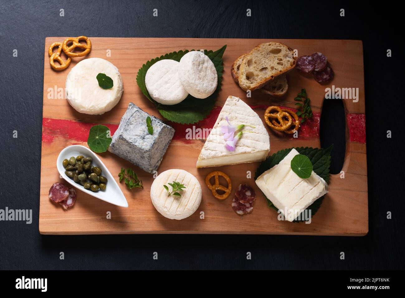 Food Concept Sortiment französischer Bio-Frischkäse aus Ziege auf Holzkäseplatte auf schwarzem Hintergrund mit Kopierfläche Stockfoto