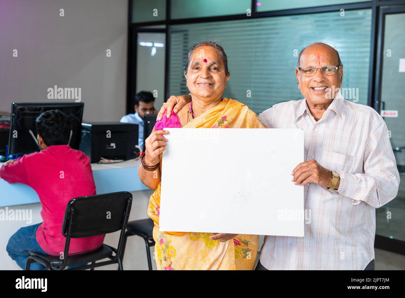 Glückliches lächelndes Senior-Paar, das weiße leere Tafel oder Plakat zeigt, indem es mit der Kamera auf die Bank schaut - Konzept der Werbung, Finanzen oder Versicherung Stockfoto