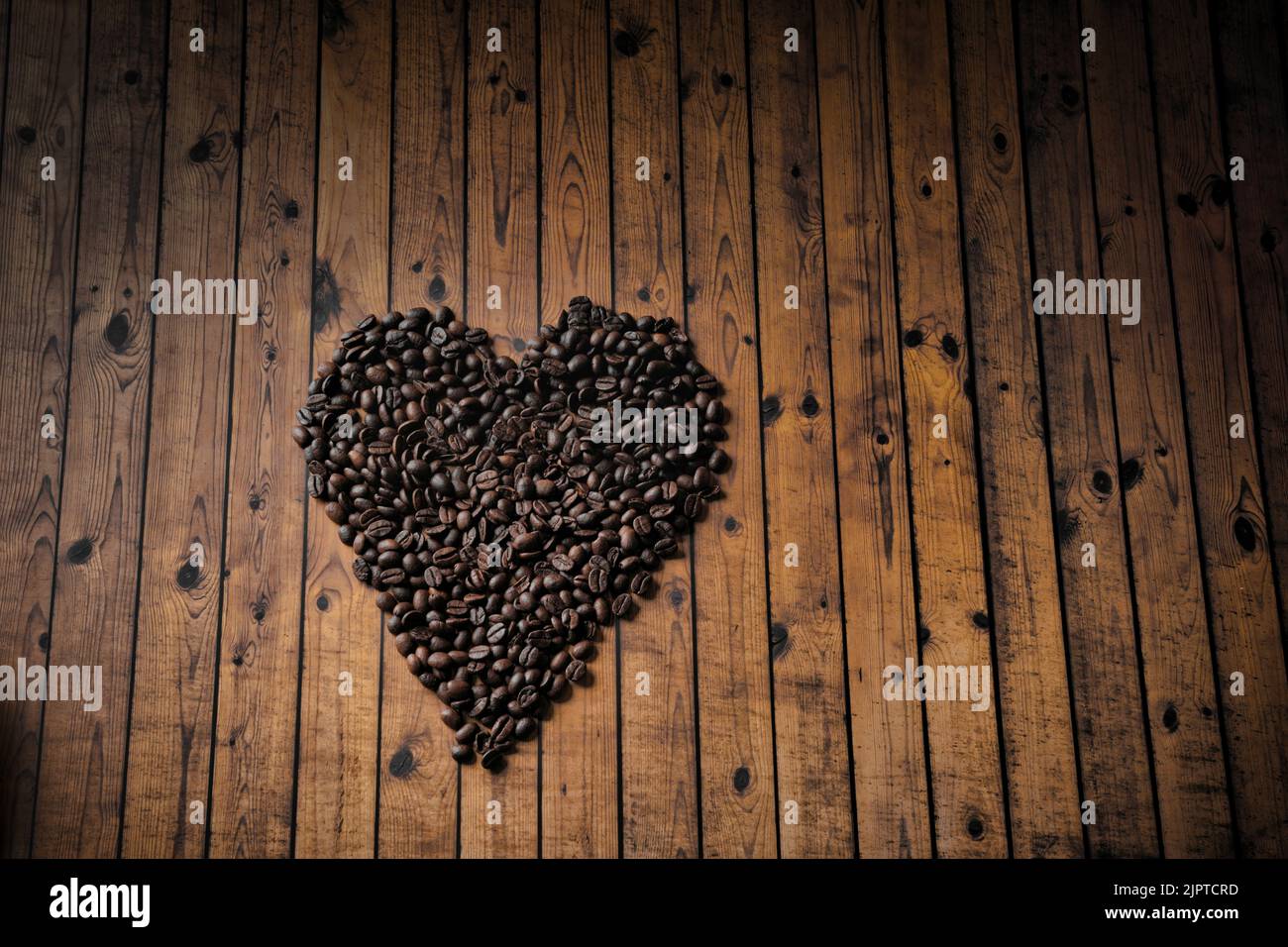 Die Herzform aus Kaffeebohnen auf Holzoberfläche. Stockfoto