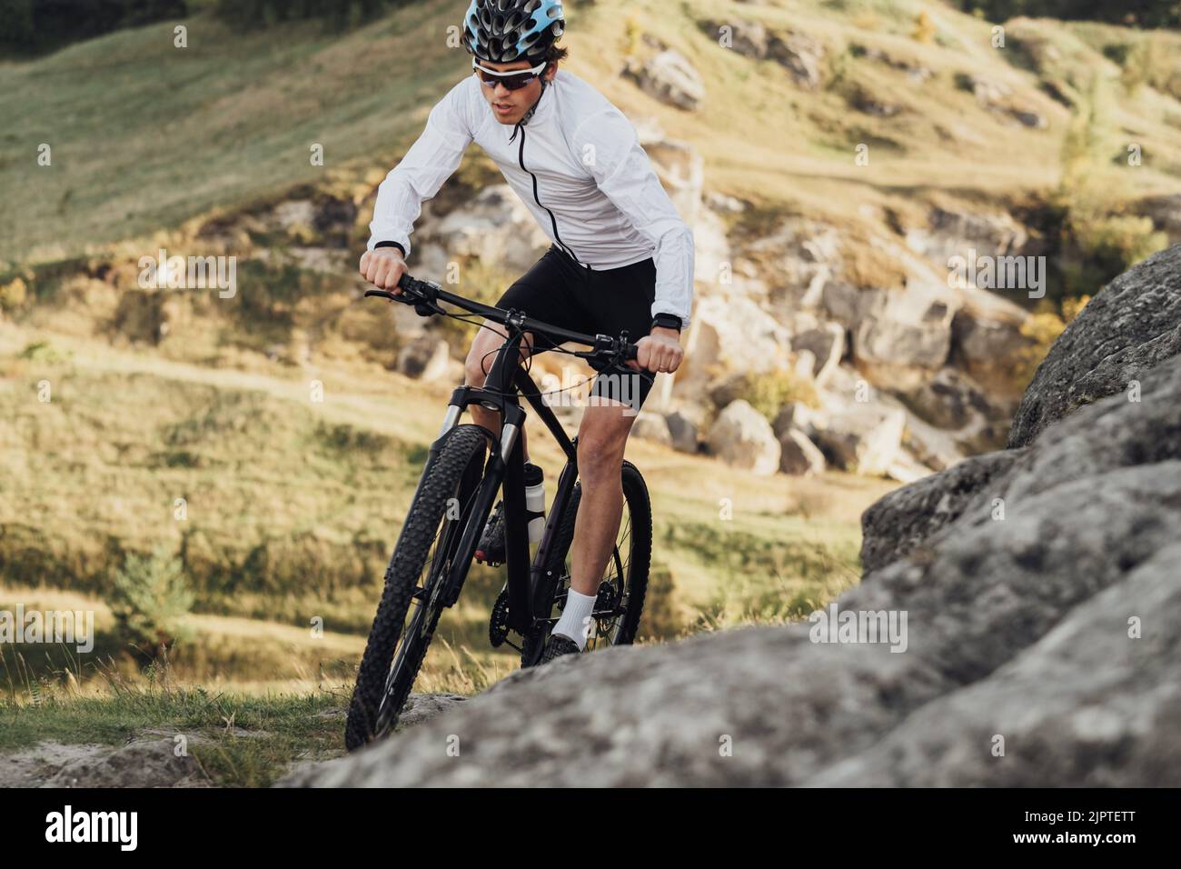 Nahaufnahme professioneller Radsportler mit Mountainbike auf dem Trail im felsigen Gelände Stockfoto