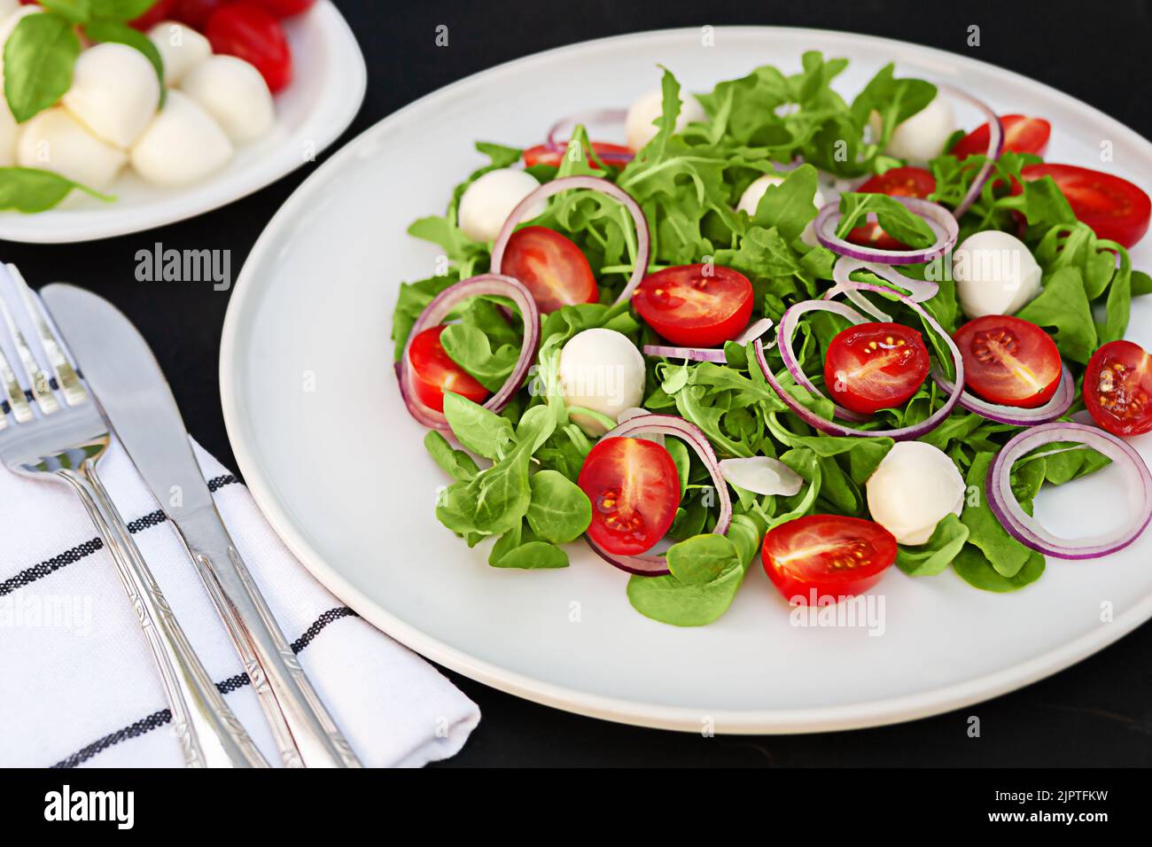 Vegetarischer frischer Gemüsesalat mit Mozzarella auf einem weißen Gericht in Nahaufnahme Stockfoto