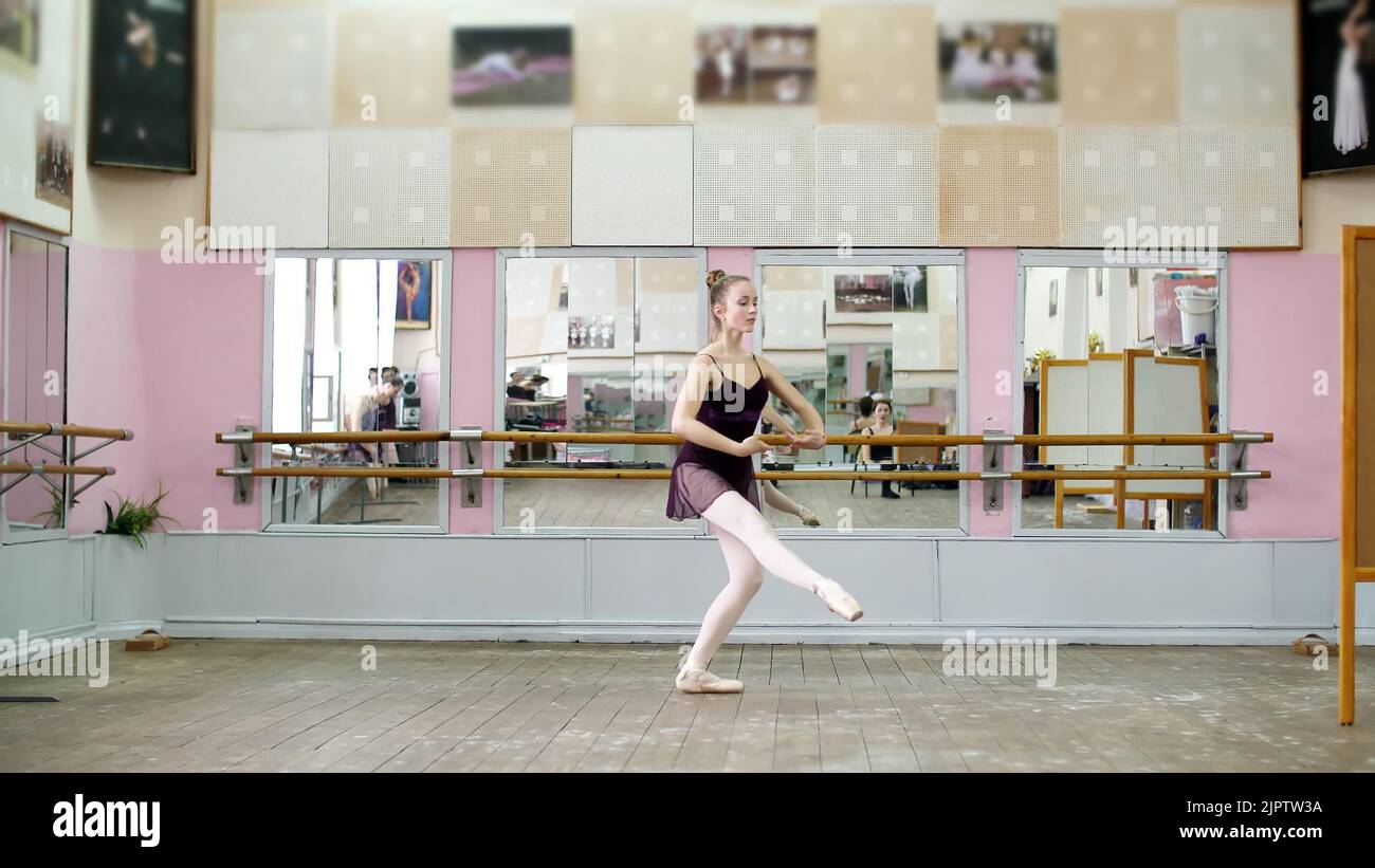 In der Tanzhalle spielt die junge Ballerina in schwarzem Trikot pas courru , pointe , sie bewegt sich elegant durch die Ballettklasse. Hochwertige Fotos Stockfoto