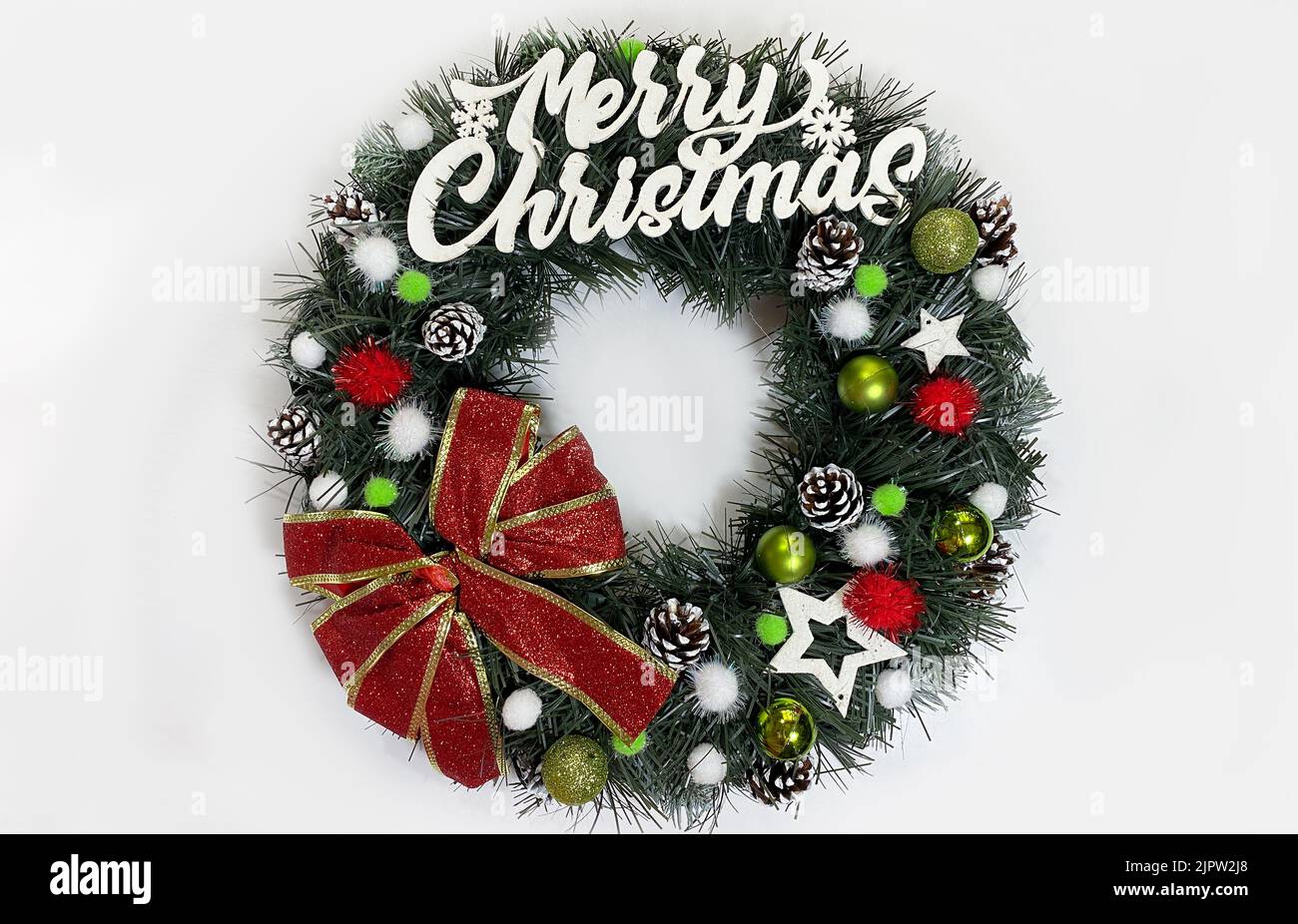 Weihnachtskranz, der die Haustür für die Feiertage aus Fichte, silbernen Bögen, Sternen und Weihnachtskugeln auf weißem Hintergrund isoliert ziert Stockfoto