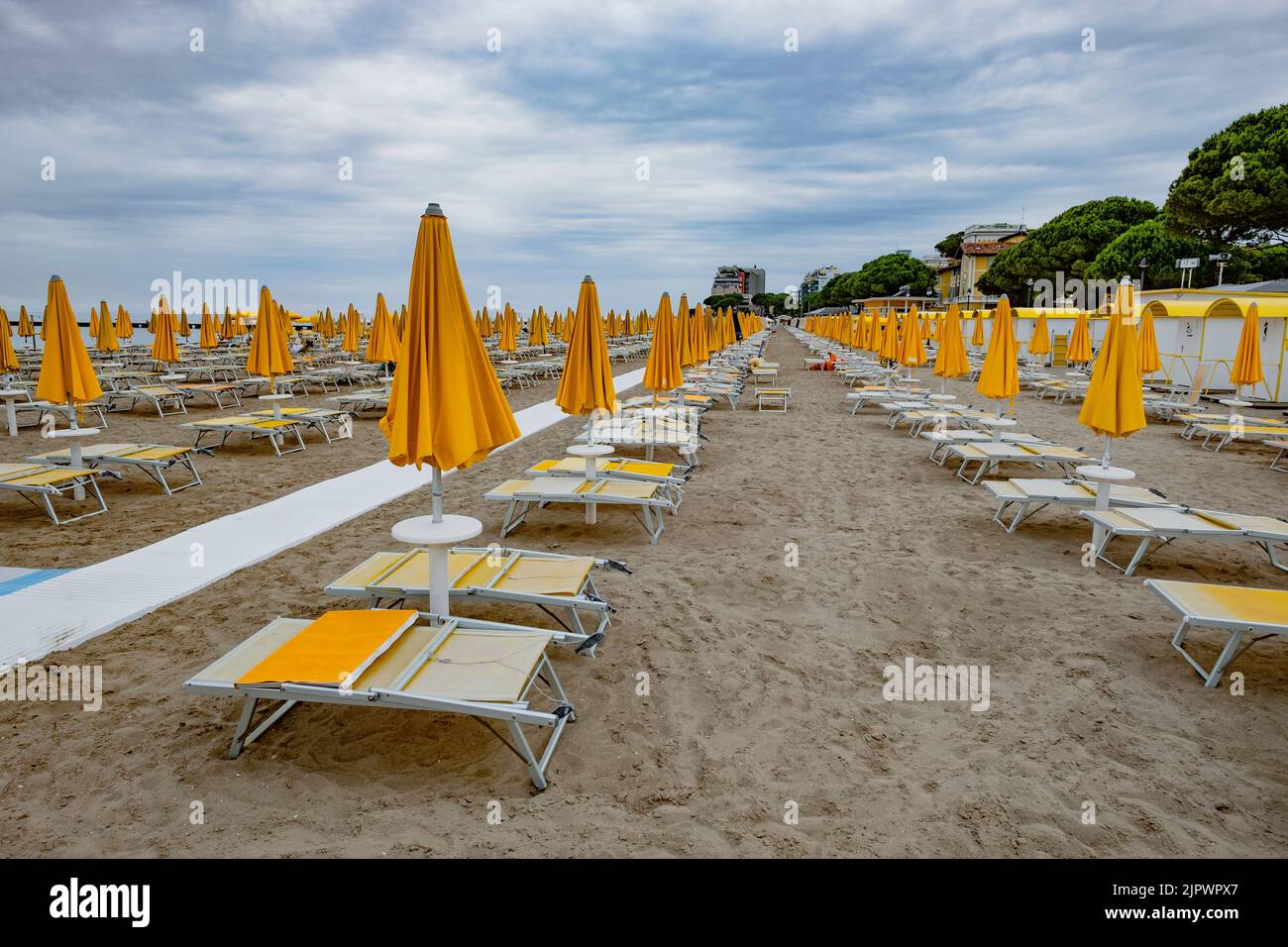 Leerer Strand an der Adriaküste. Geschlossene Sonnenschirme leeren die Sonnenliegen. Ende der Touristensaison Stockfoto