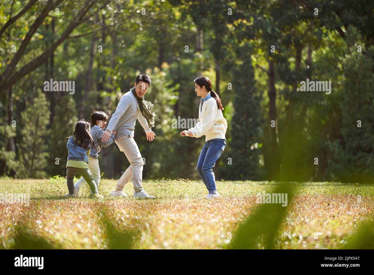 Junge asiatische Familie mit zwei Kindern, die Spaß beim Spielen im Park haben Stockfoto