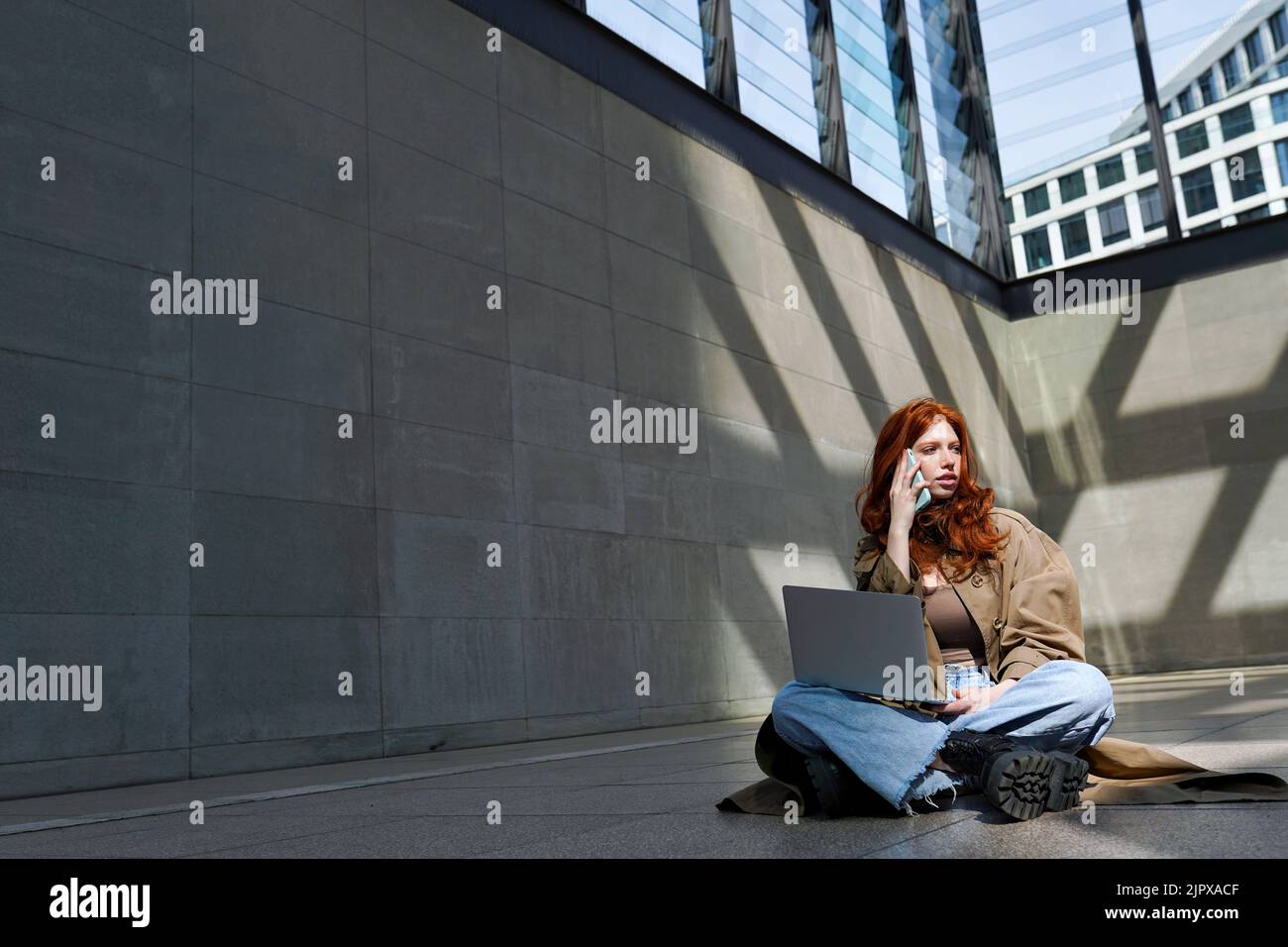 Teen Rotschopf Mädchen mit Laptop reden auf Zelle in der Stadt städtischen Standort. Stockfoto