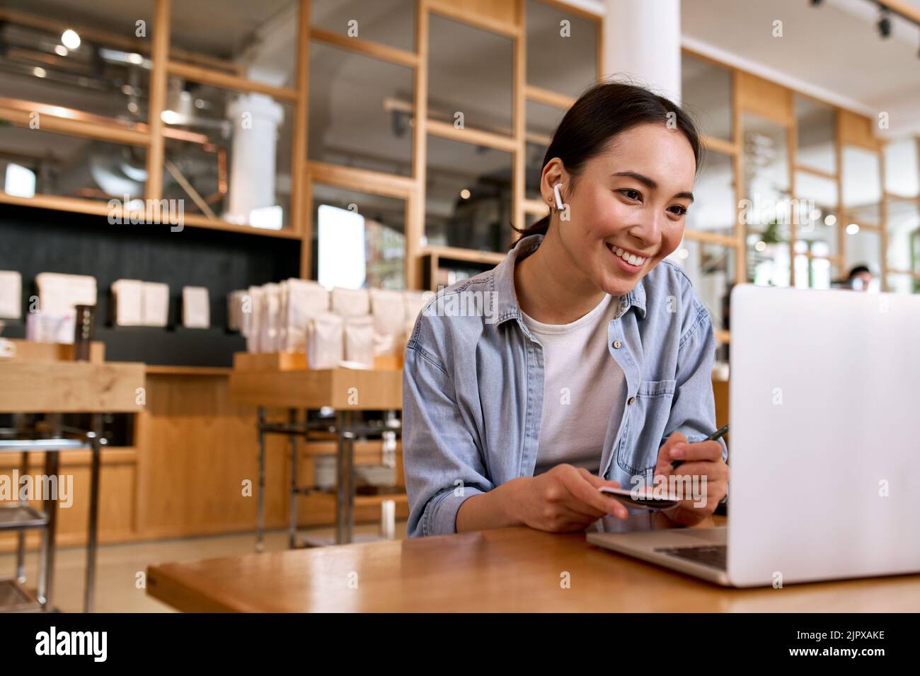 Junge lächelnde asiatische Studentin, die sich Online-Webinar-Schulungen auf einem Laptop ansieht. Stockfoto