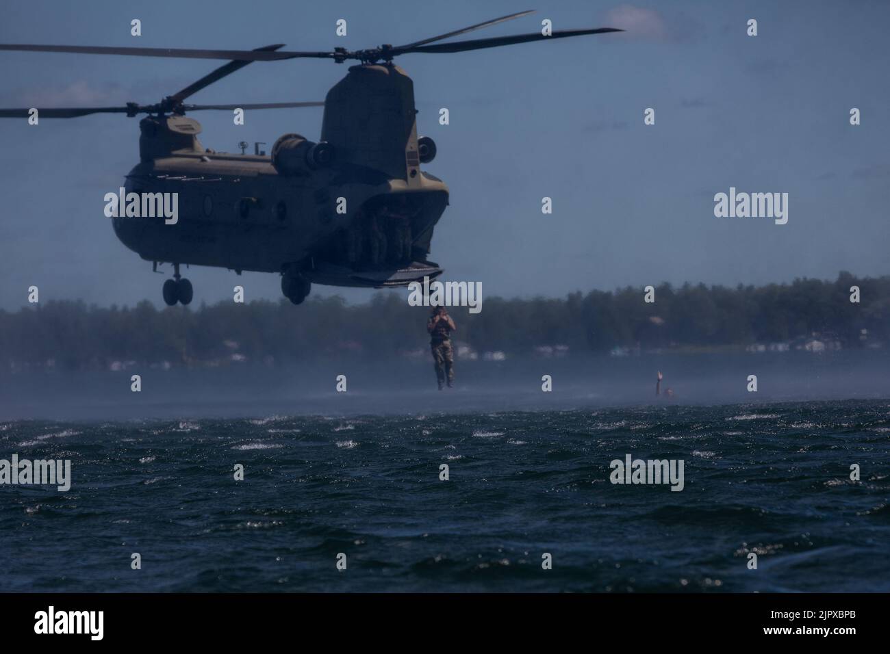 Ein Soldat der 20. Special Forces Group (Airborne) springt aus einem CH-47 Chinook, der 2. Squadron, 107. Cavalry Regiment, Ohio National Guard, zugewiesen wurde, in das Wasser des Lake Margrethe im Camp Greyling, Michigan, während einer Helocast-Übung für Soldaten, die die Einheit durch Northern Strike 22, 11. August 2022 unterstützen. Ein Helokast ist eine Einfügemethode, die von speziellen Einsatzkräften verwendet wird, bei der ein Hubschrauber über ein Gewässer fliegt, um ein Boot und Soldaten, die ausspringen, zum Boot schwimmen und sich zu ihrem Ziel an Land bewegen, abzusetzen. (USA Foto der Armee-Nationalgarde von SPC. Cody Muzio) Stockfoto