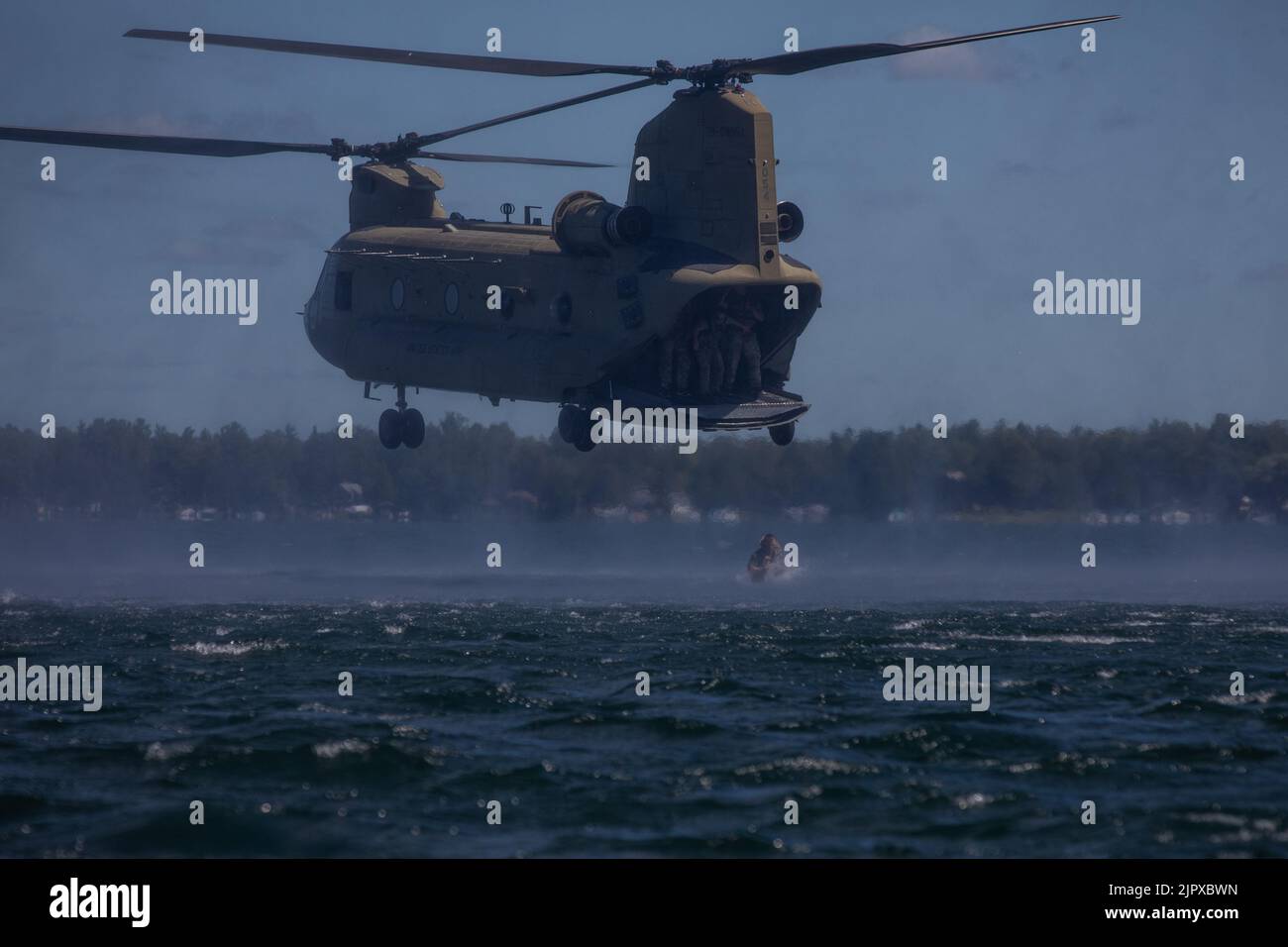 Ein Soldat der 20. Special Forces Group (Airborne) springt aus einem CH-47 Chinook, der 2. Squadron, 107. Cavalry Regiment, Ohio National Guard, zugewiesen ist, und trifft das Wasser des Lake Margrethe in Camp Greyling, Michigan, während einer Helocast-Übung für Soldaten, die die Einheit durch Northern Strike 22, 11. August 2022 unterstützen. Ein Helokast ist eine Einfügemethode, die von speziellen Einsatzkräften verwendet wird, bei der ein Hubschrauber über ein Gewässer fliegt, um ein Boot und Soldaten, die ausspringen, zum Boot schwimmen und sich zu ihrem Ziel an Land bewegen, abzusetzen. (USA Foto der Armee-Nationalgarde von SPC. Cody Muzio) Stockfoto