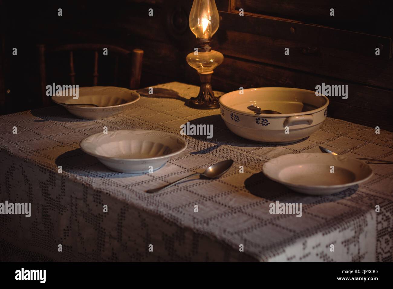 Blick auf Glaswaren auf einem Tisch mit Öllampe in einem dunklen Raum Stockfoto