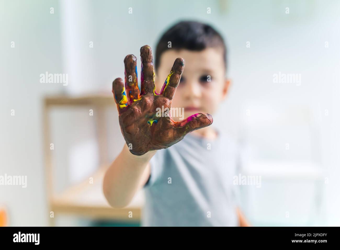 Kleinkind Junge zeigt seine bunte Handfläche mit waschbaren und ungiftigen Farben bemalt nach einem Kunstspiel im Kindergarten. Fingermalerei für Kinder sensorische Fähigkeiten, Kreativität und Vorstellungskraft Entwicklung. Hochwertige Fotos Stockfoto