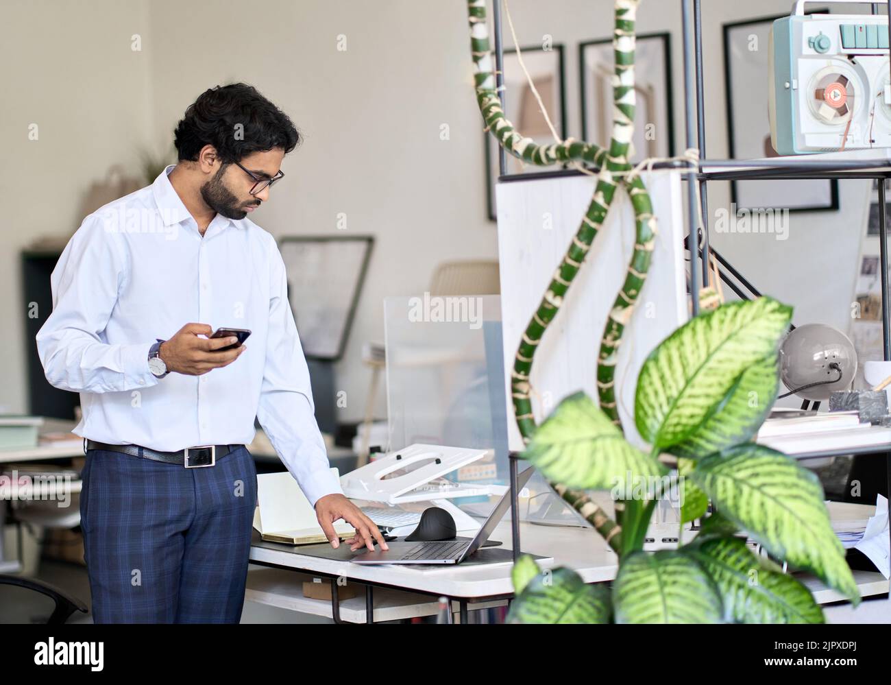 Geschäftiger indischer Geschäftsmann, der bei der Arbeit in modernen Bürorällen steht. Stockfoto