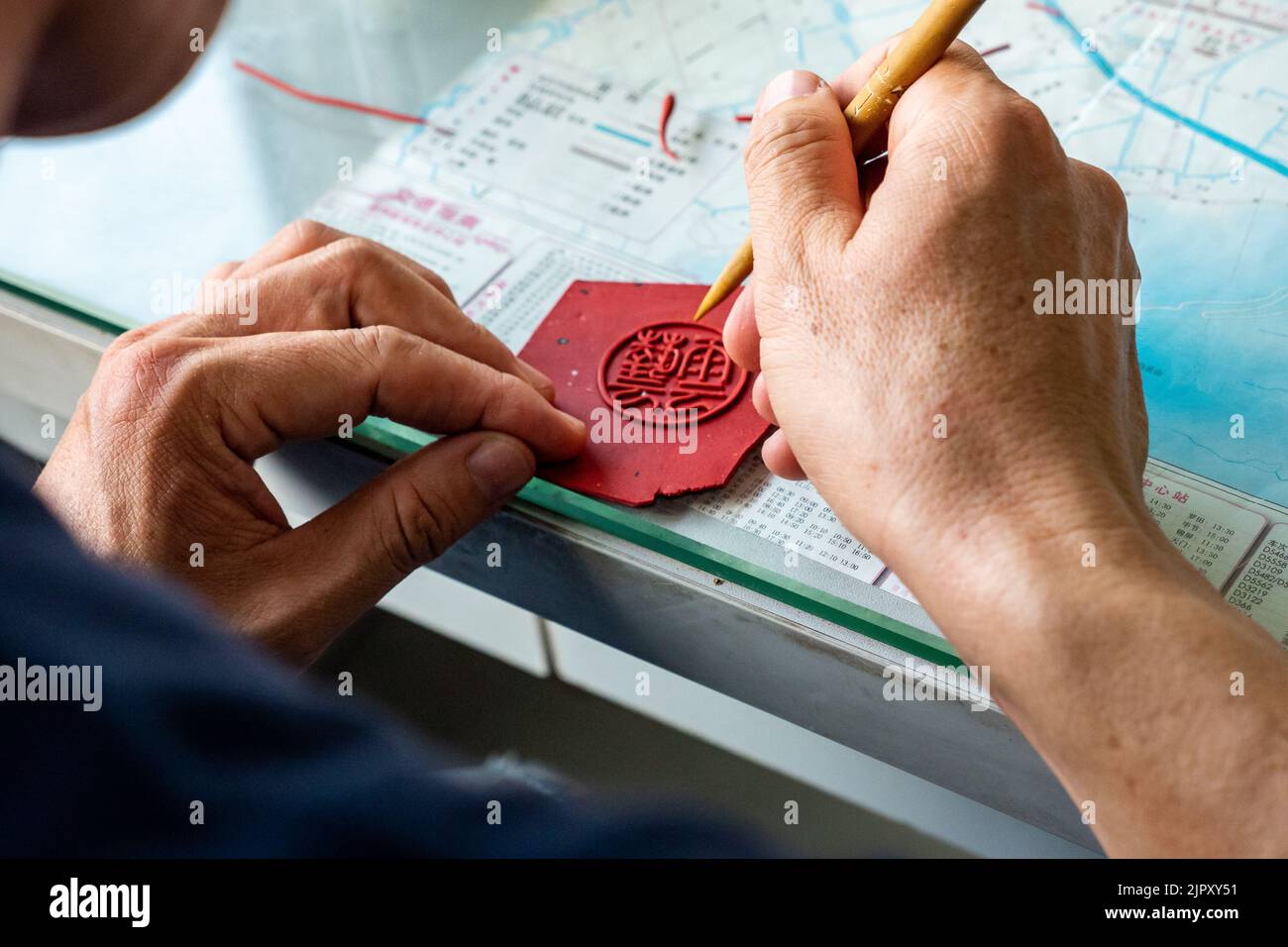 Ein chinesischer Handwerker ätzt Details auf das Stempelsiegel Stockfoto