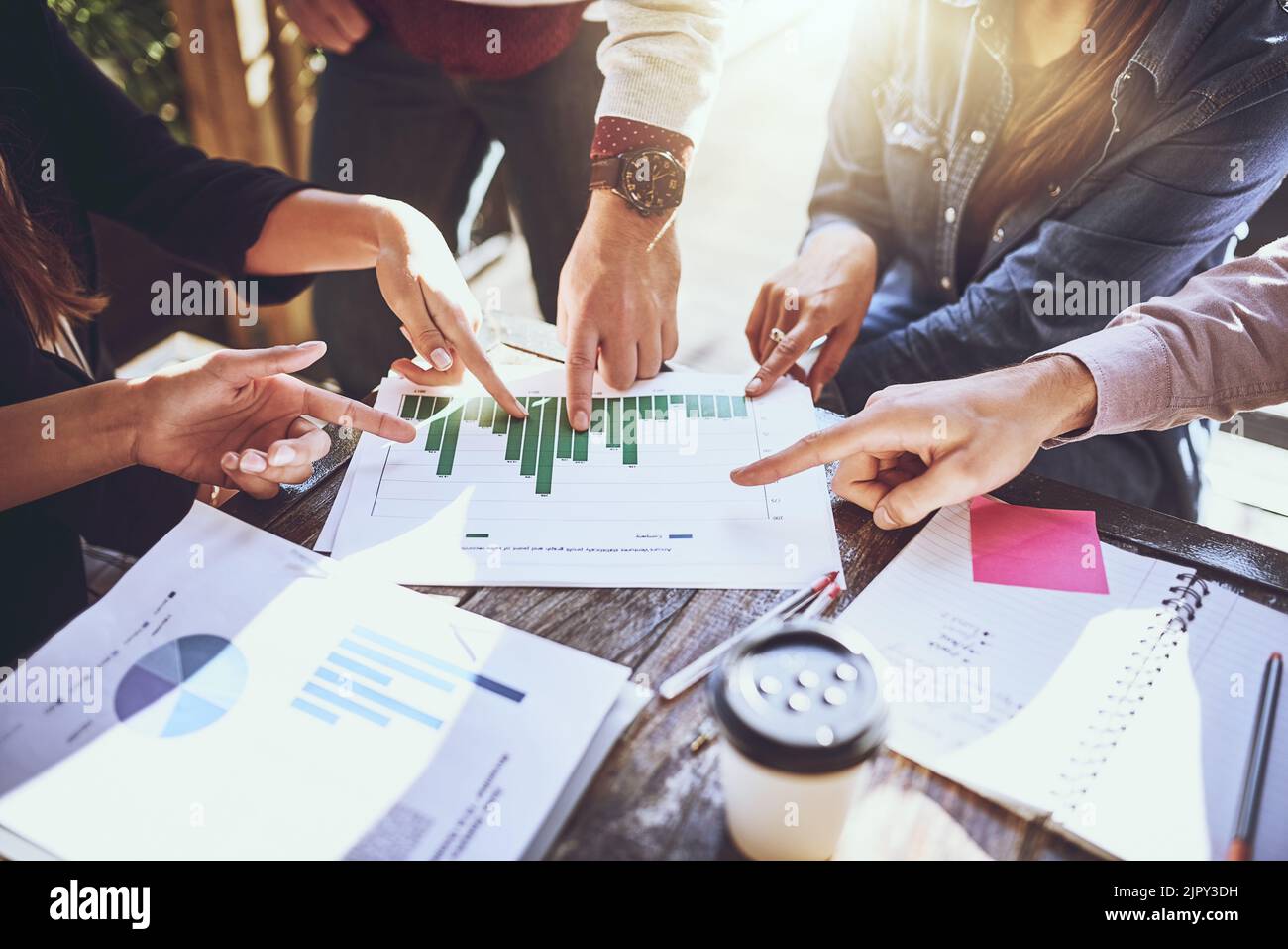 Eine Gruppe von Kollegen, die während eines Meetings in einem Café über Schreibarbeit diskutiert haben. Stockfoto