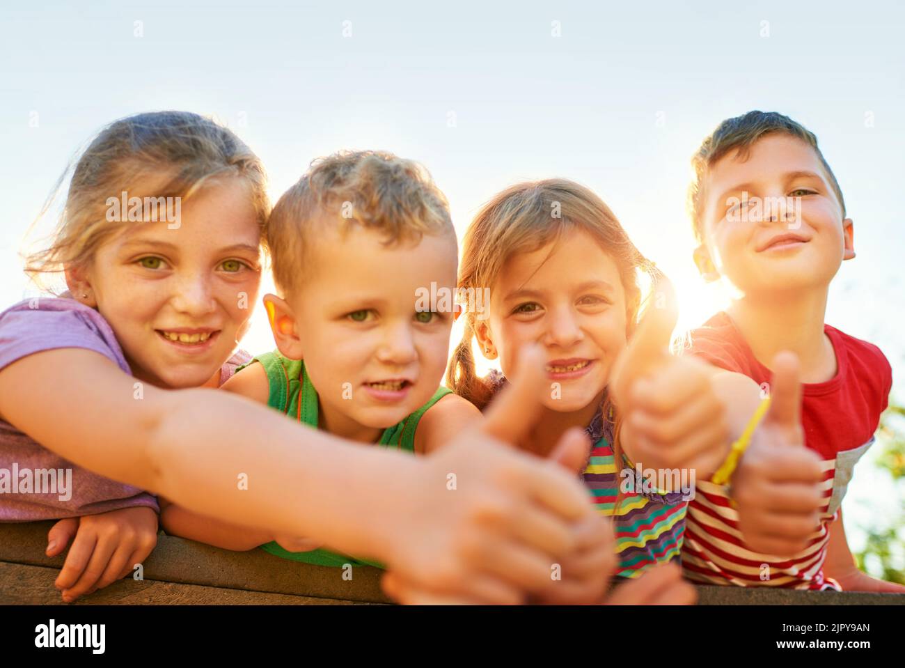 Spielzeit ist die beste Zeit. Porträt einer Gruppe von kleinen Kindern, die Daumen hoch zeigen, während sie im Freien zusammen spielen. Stockfoto
