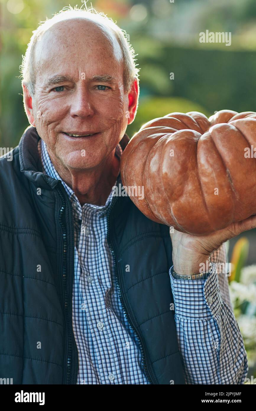 Meine Frau wird dieses Hotel wegen der Torte lieben. Porträt eines älteren Mannes, der einen Kürbis draußen hält. Stockfoto