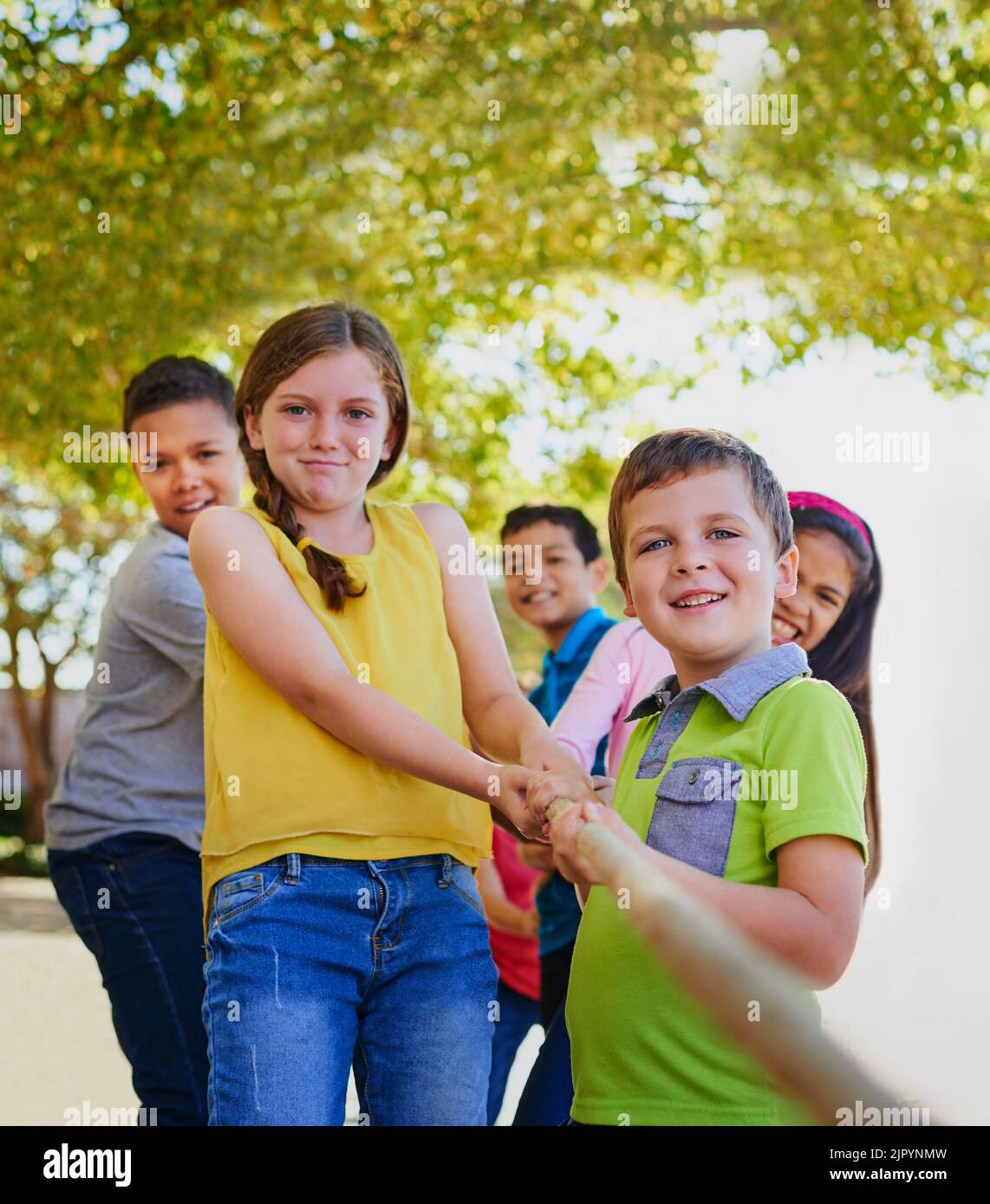 Gemeinsam sind wir viel stärker. Eine vielfältige Gruppe von Kindern spielt draußen an einem Tauziehen. Stockfoto