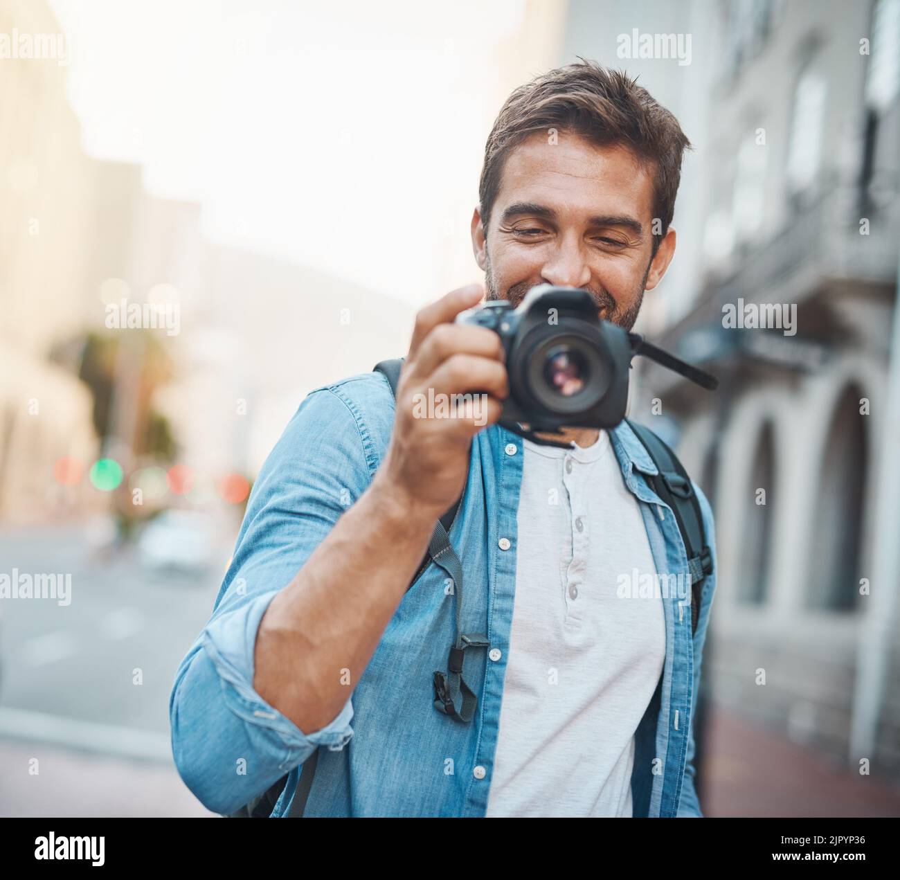 Die Fotografie macht Sie sich Ihrer Umgebung bewusst. Ein junger Mann, der Fotos macht, während er eine fremde Stadt erkundet. Stockfoto