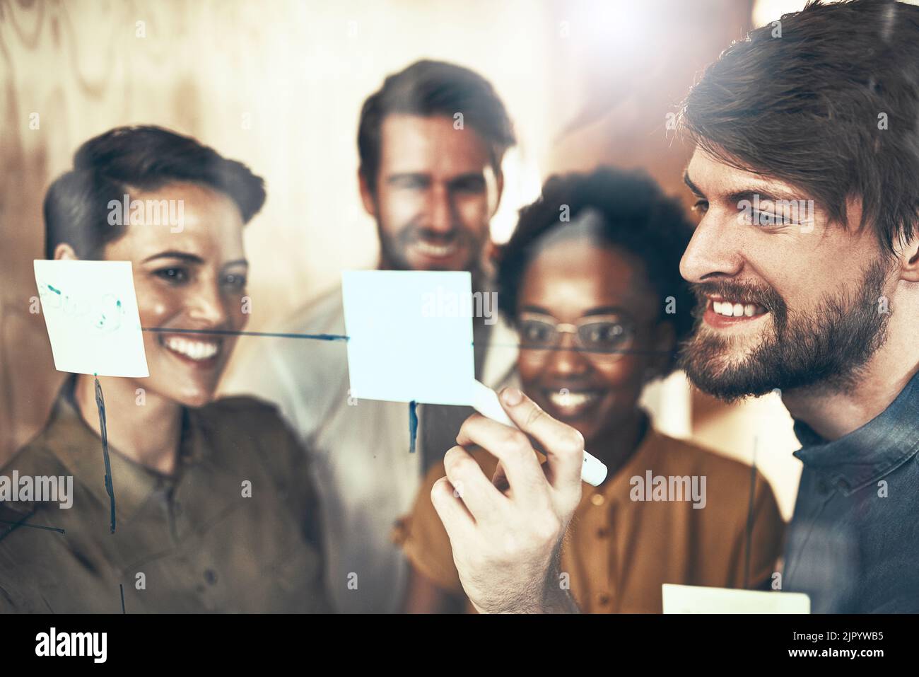 Eine Gruppe von Geschäftsleuten, die mit Notizen an einer Glaswand Brainstorming. Stockfoto