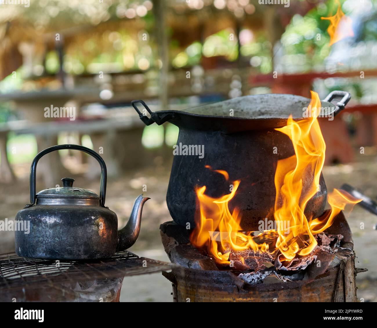 Ein großer schwarzer Topf und ein alter Wasserkocher auf einem Feuer im Freien. Stockfoto