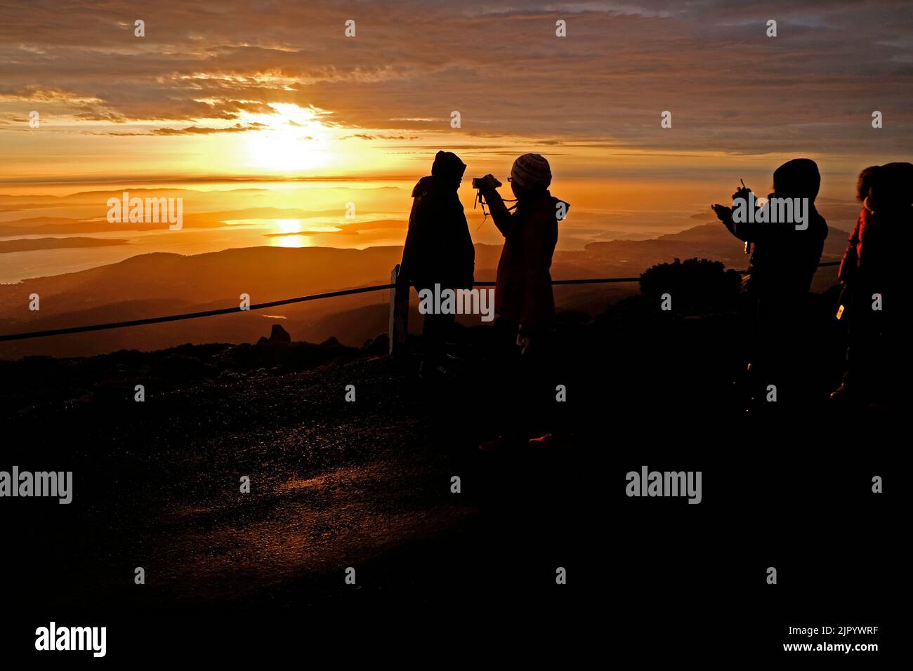 Touristen, die den Sonnenaufgang vom Gipfel des kunanyi/Mt Wellington in Hobart Tasmanien aus beobachten (Höhe 1271 Meter über dem Meeresspiegel) Stockfoto