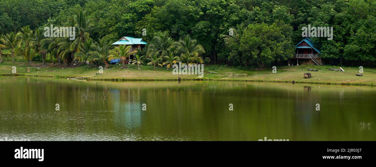 Eine verträumte Landschaft, ein kleines Haus in tropischen üppigen grünen Wäldern, an einem ruhigen See. Stockfoto