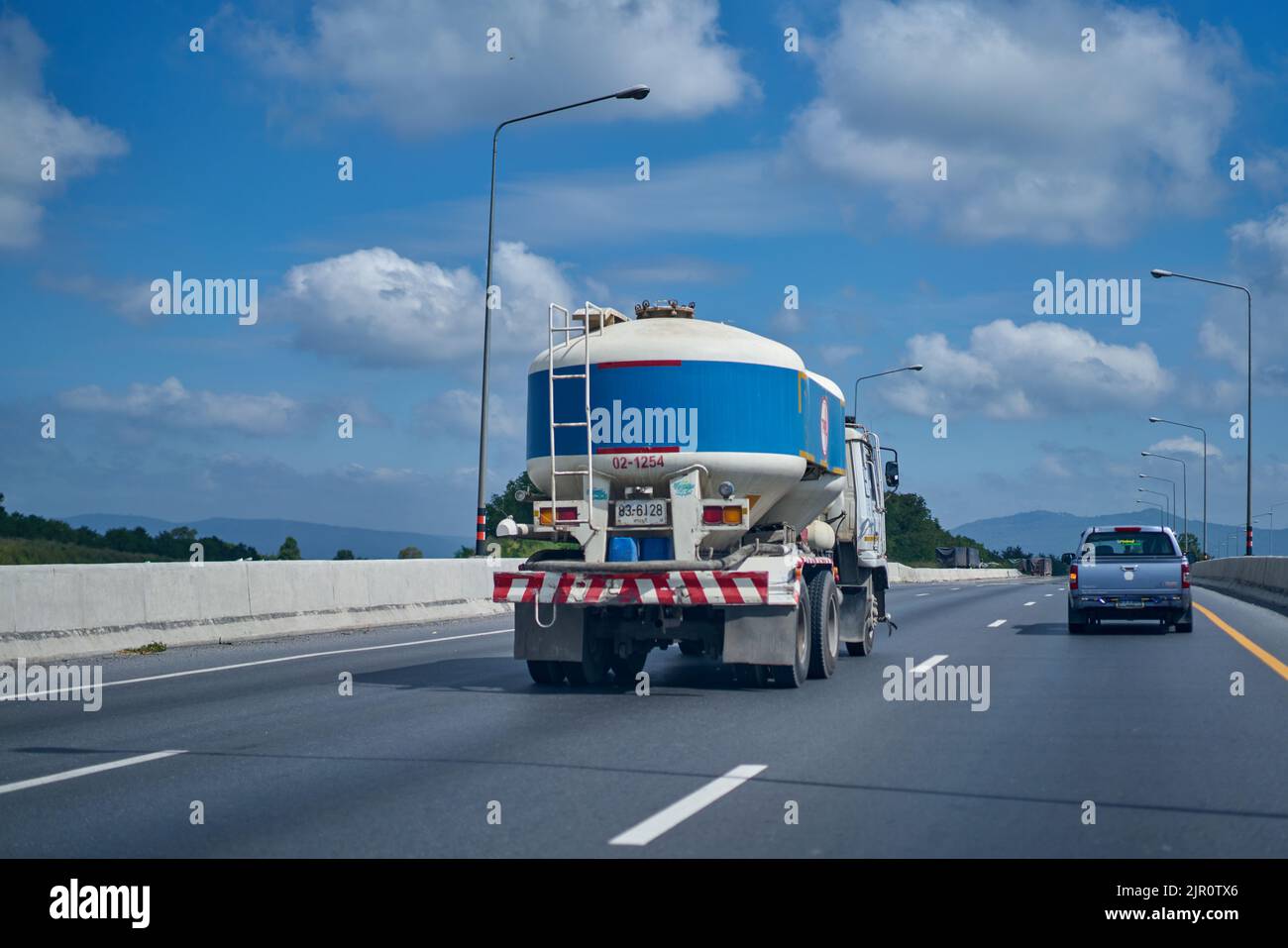 Blauer Zement-LKW auf einer Autobahn unter einem blauen Himmel mit weißen Wolken. Stockfoto