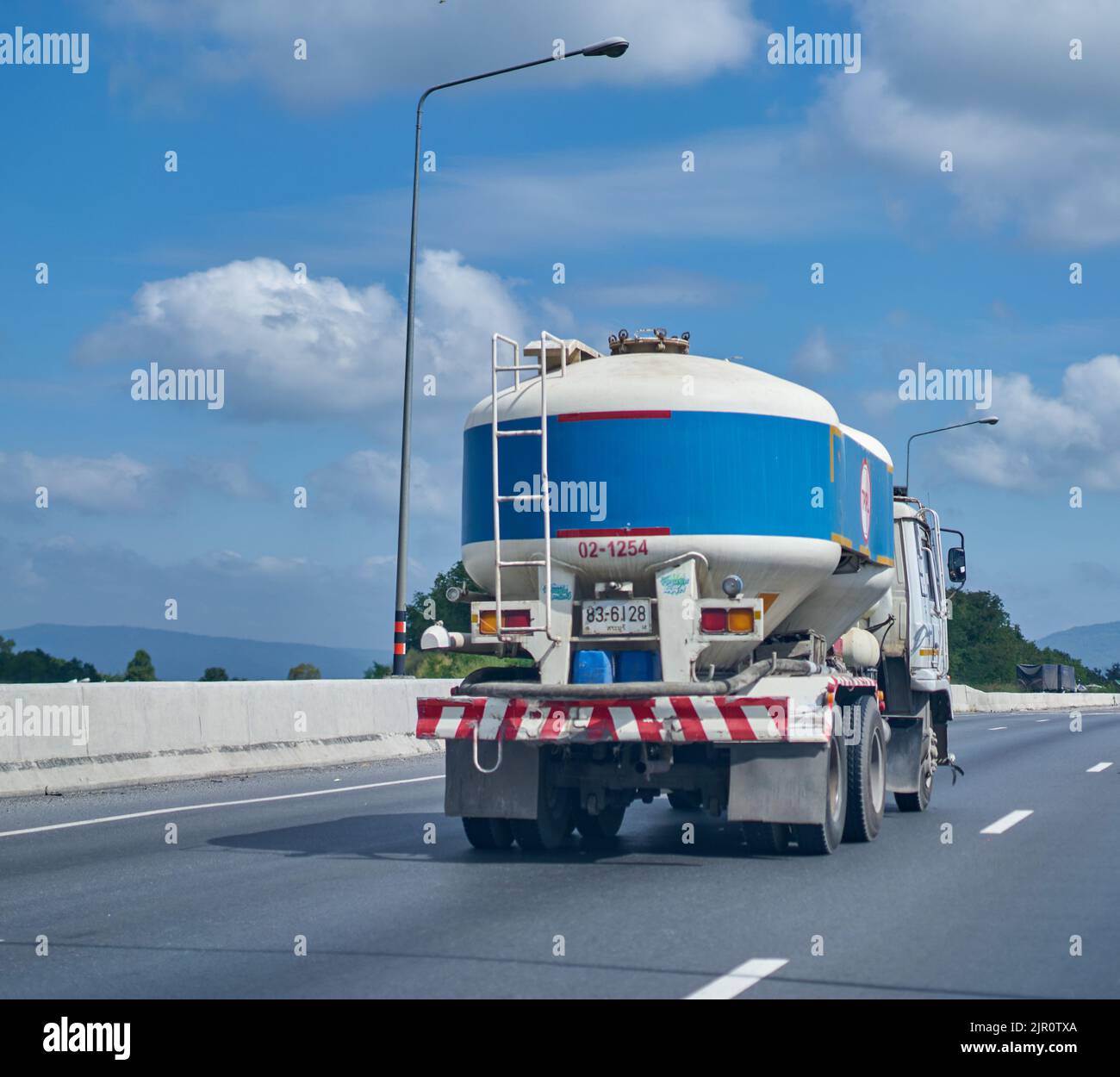 Blauer Zement-LKW auf einer Autobahn unter einem blauen Himmel mit weißen Wolken. Stockfoto