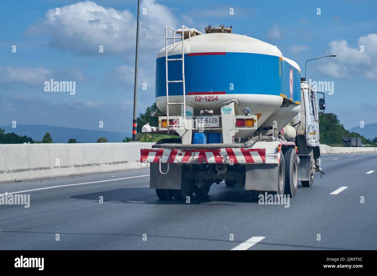 Blauer Zement-LKW auf einer Autobahn unter einem blauen Himmel mit weißen Wolken. Stockfoto
