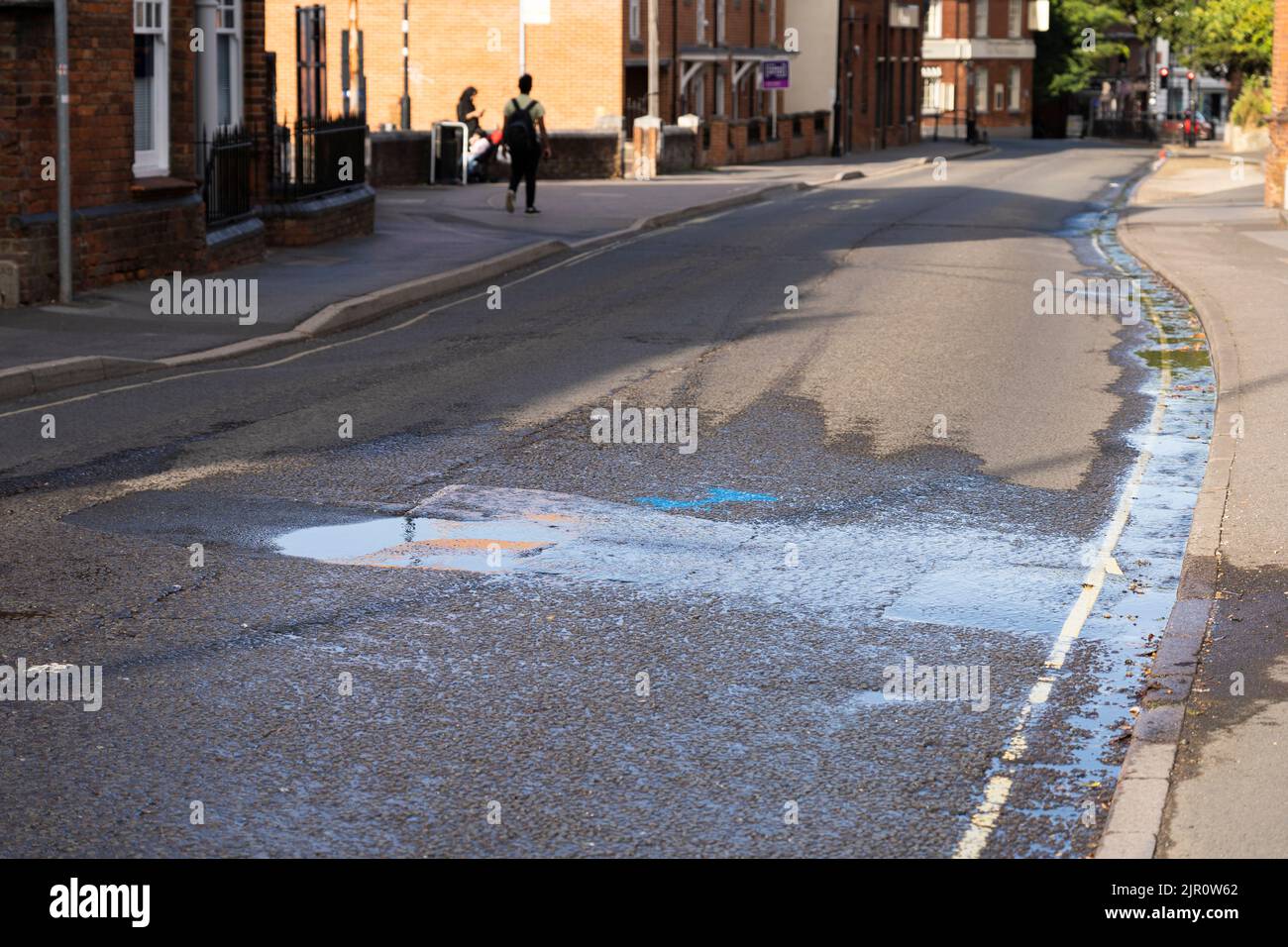 Am Ende der Dürre von 2022 führt ein platztes Wasserrohr auf der Winchester Road dazu, dass Wasser auf der Straße ausläuft und im Abfluss verloren geht. Basingstoke. VEREINIGTES KÖNIGREICH Stockfoto