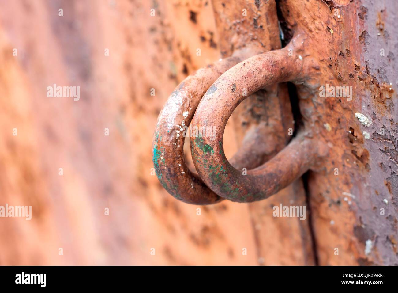 Eiserne Scharniere für ein Vorhängeschloss an einer Metalltür mit alter gerissener Farbe und Rost. Textur und Hintergrund Stockfoto