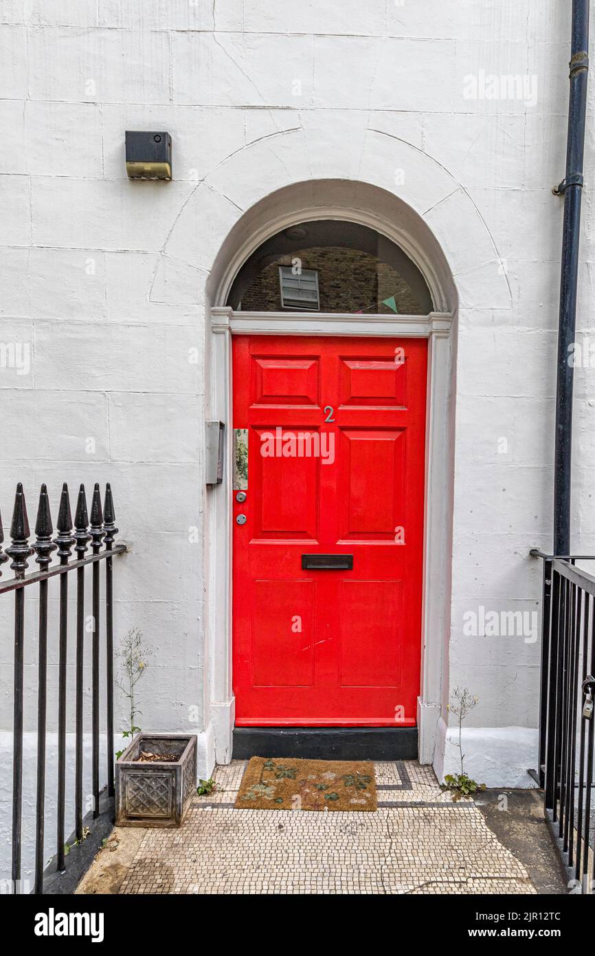 Ein weiß gestrichenes Haus mit einer roten Eingangstür und einem Fensterbogen über dem Haus in Fitzrovia, London W1 Stockfoto