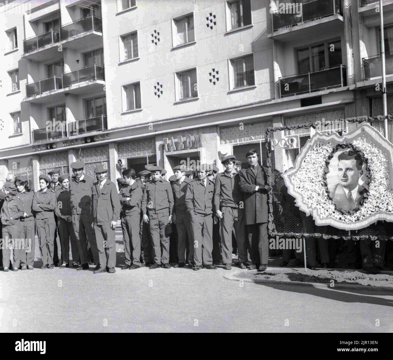 Arbeiter nach einem Porträt des rumänischen kommunistischen Präsidenten Nicolae Ceausescu, ca. 1979. Während seiner Besuche im Land wurden die Menschen dazu gezwungen, ihre Liebe und Wertschätzung für ihren Anführer zu zeigen. Ceausescus Porträt ist in einem Umriss Rumäniens eingefasst, der seiner nationalistischen Politik entspricht. Stockfoto