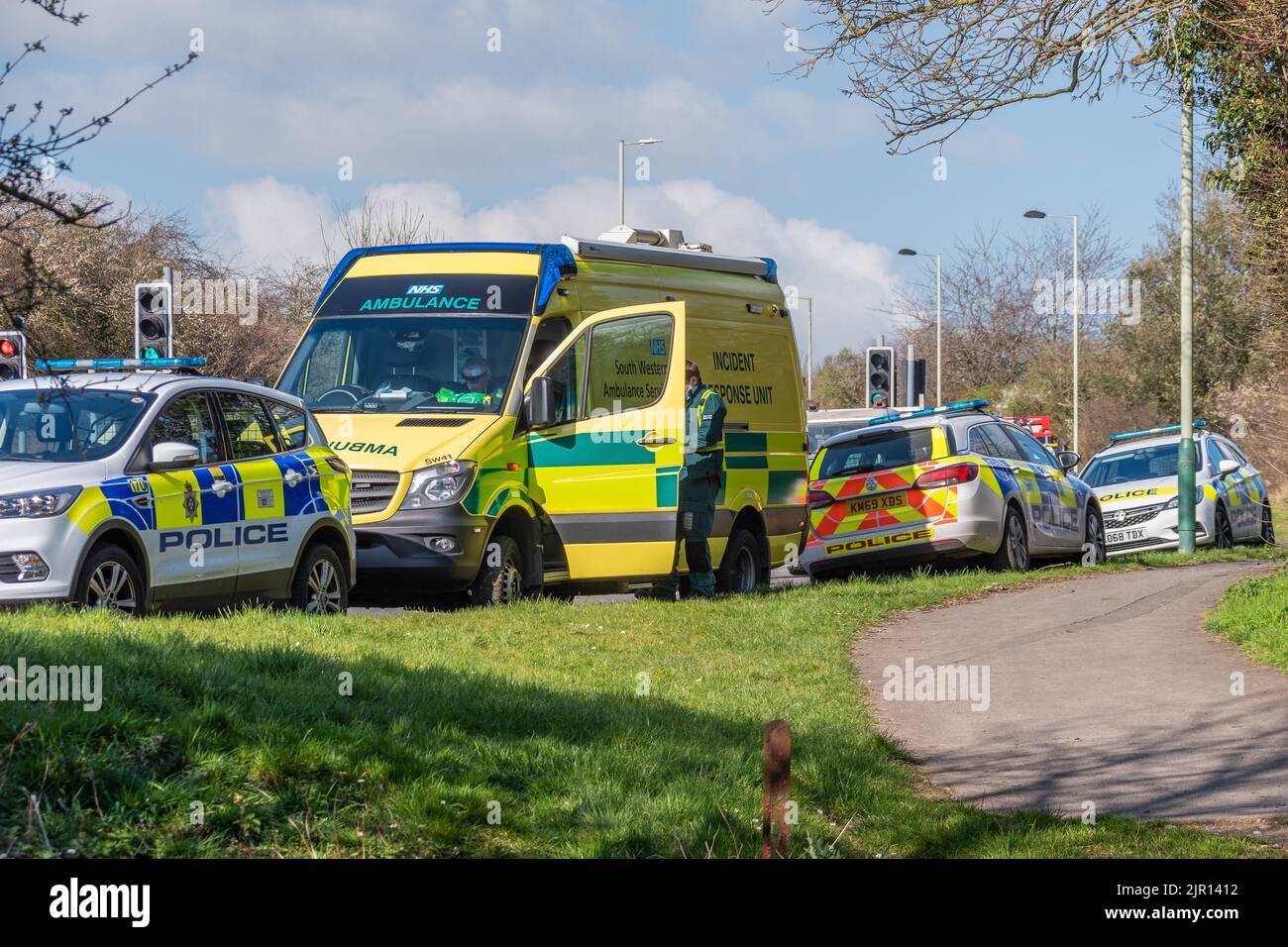 Ein Rettungsdienst aus dem Südwesten und 3 Polizeiautos der Wiltshire-Polizei parkten auf einem Grasrand zwischen Pfad und Straße, die auf ein EM reagierten Stockfoto