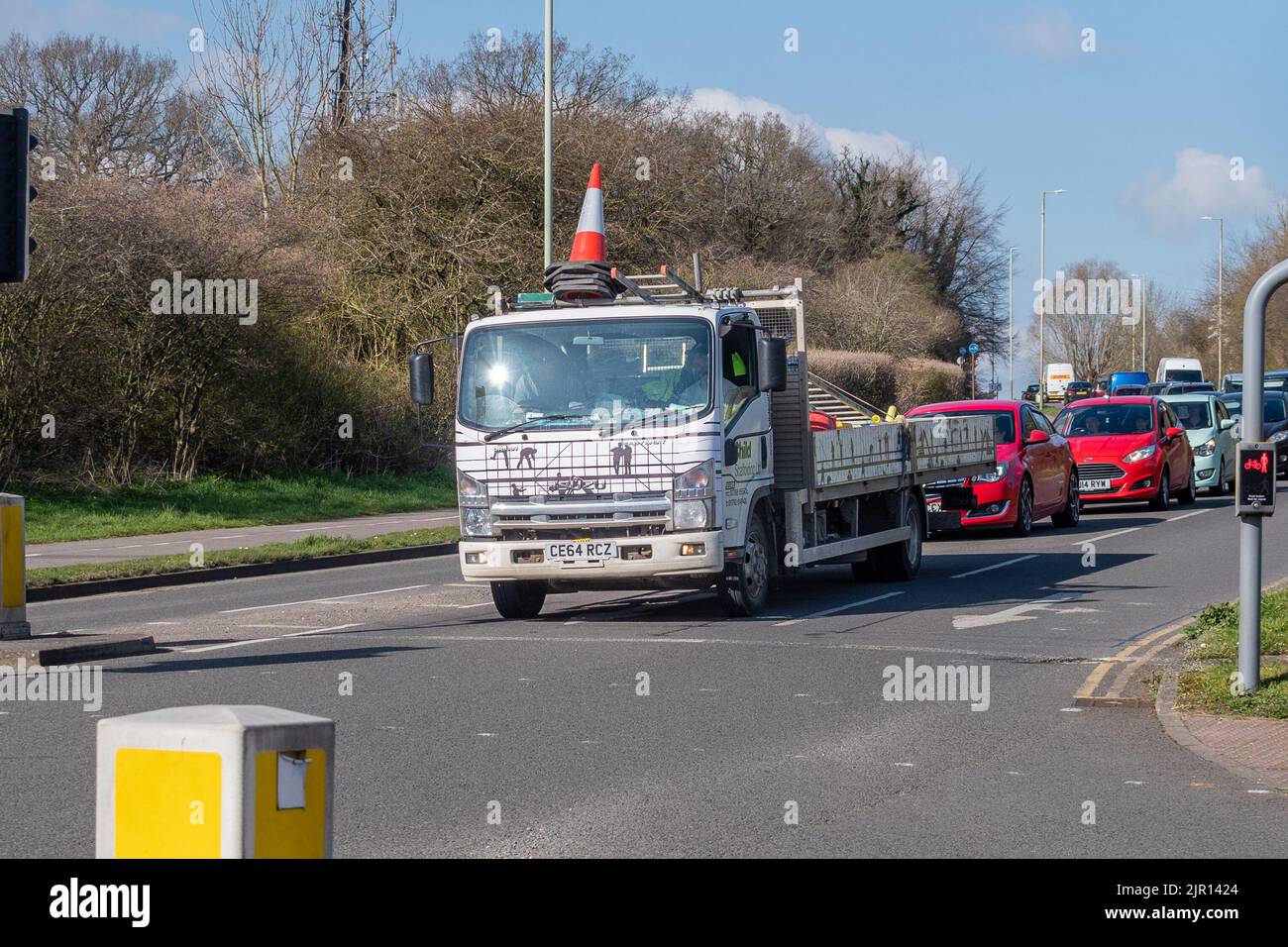 Ein Isuzu Urban N75,150 4x2 starrer LKW wartet an der Ampel mit einem Stapel von Verkehrskonen, die aus der Mitte des Fahrerdachs und anderen e hochragen Stockfoto