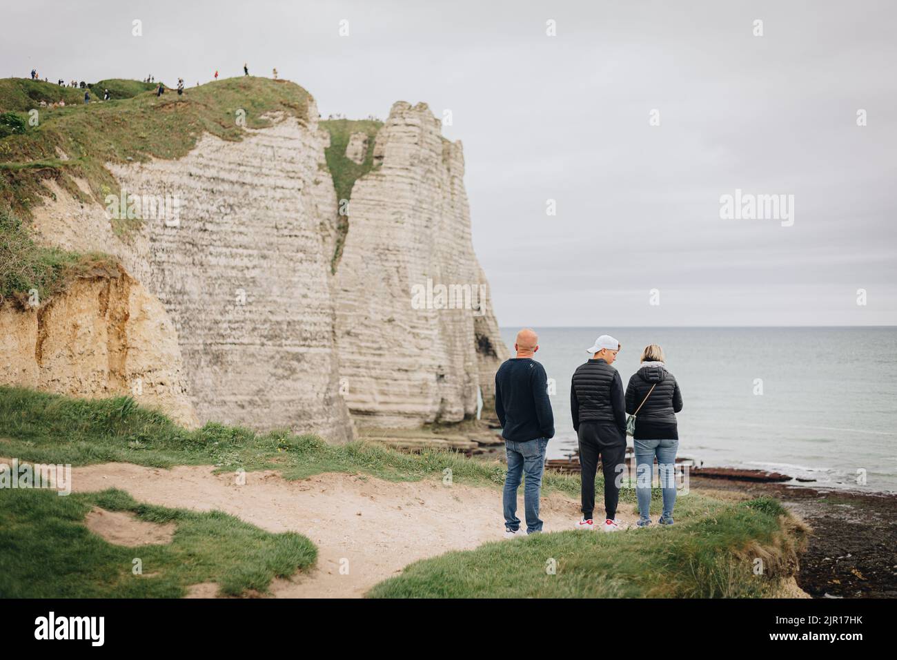 Eine Rückansicht von Menschen, die bei kaltem Wetter in Frankreich auf einer Klippe an der Küste stehen Stockfoto