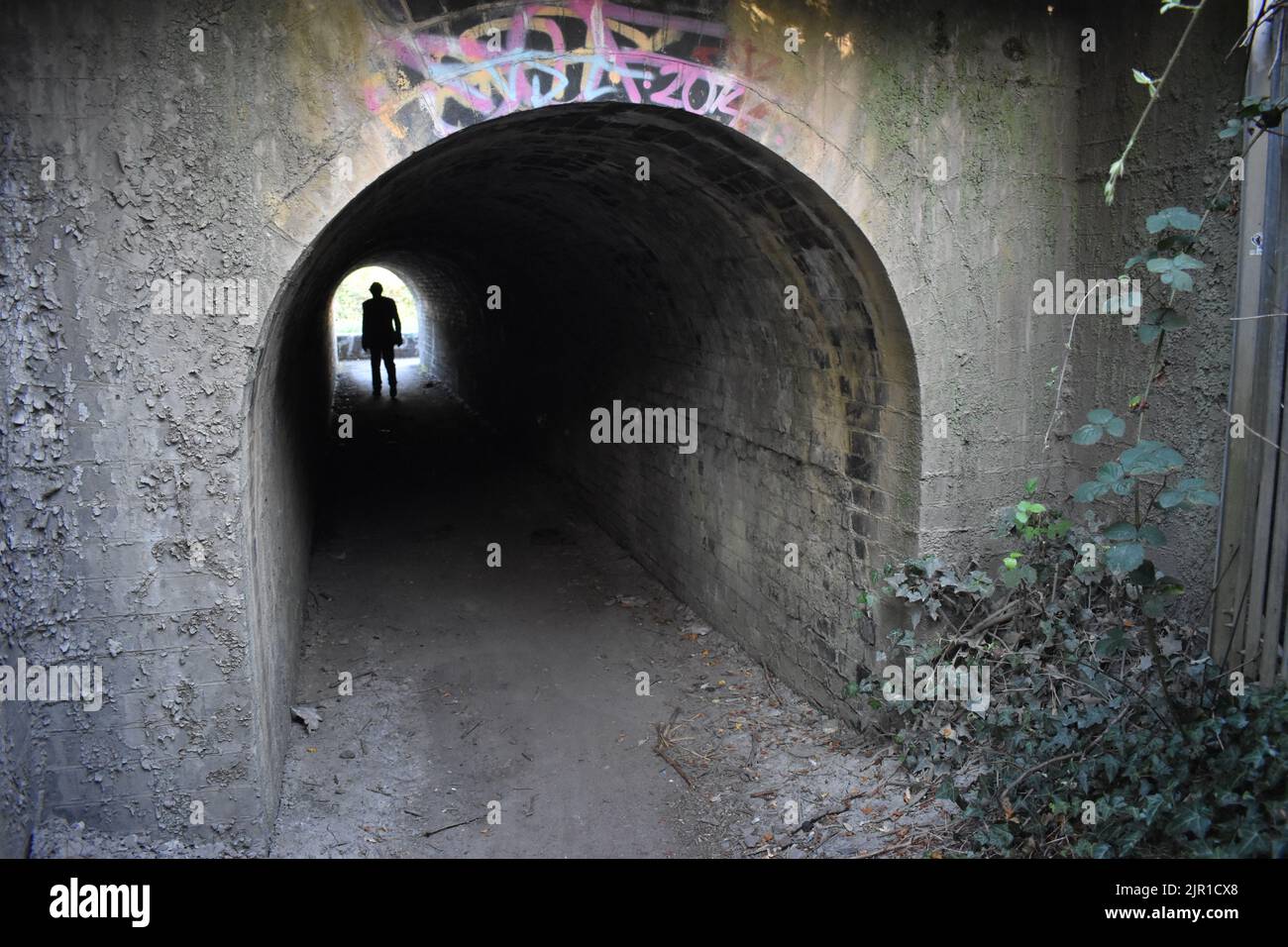 Licht am Ende des Tunnels. Eine Figur, die in Wolverton durch einen Tunnel unter der Eisenbahn läuft. Stockfoto