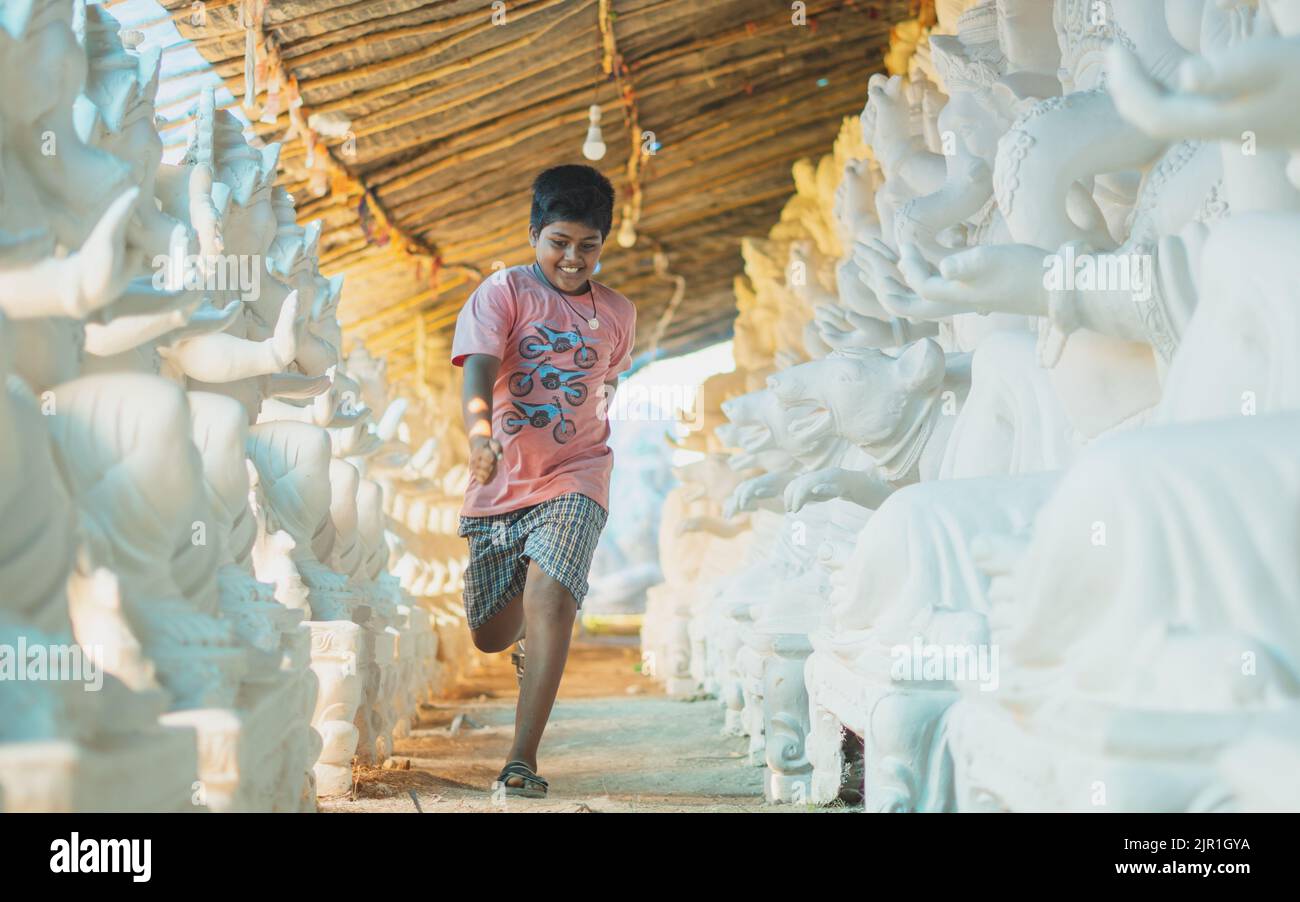 Pileru, Indien - Juli 28,2022:Fat indian Kind läuft in ganesha Idols. Fröhliches Laufkind. Stockfoto