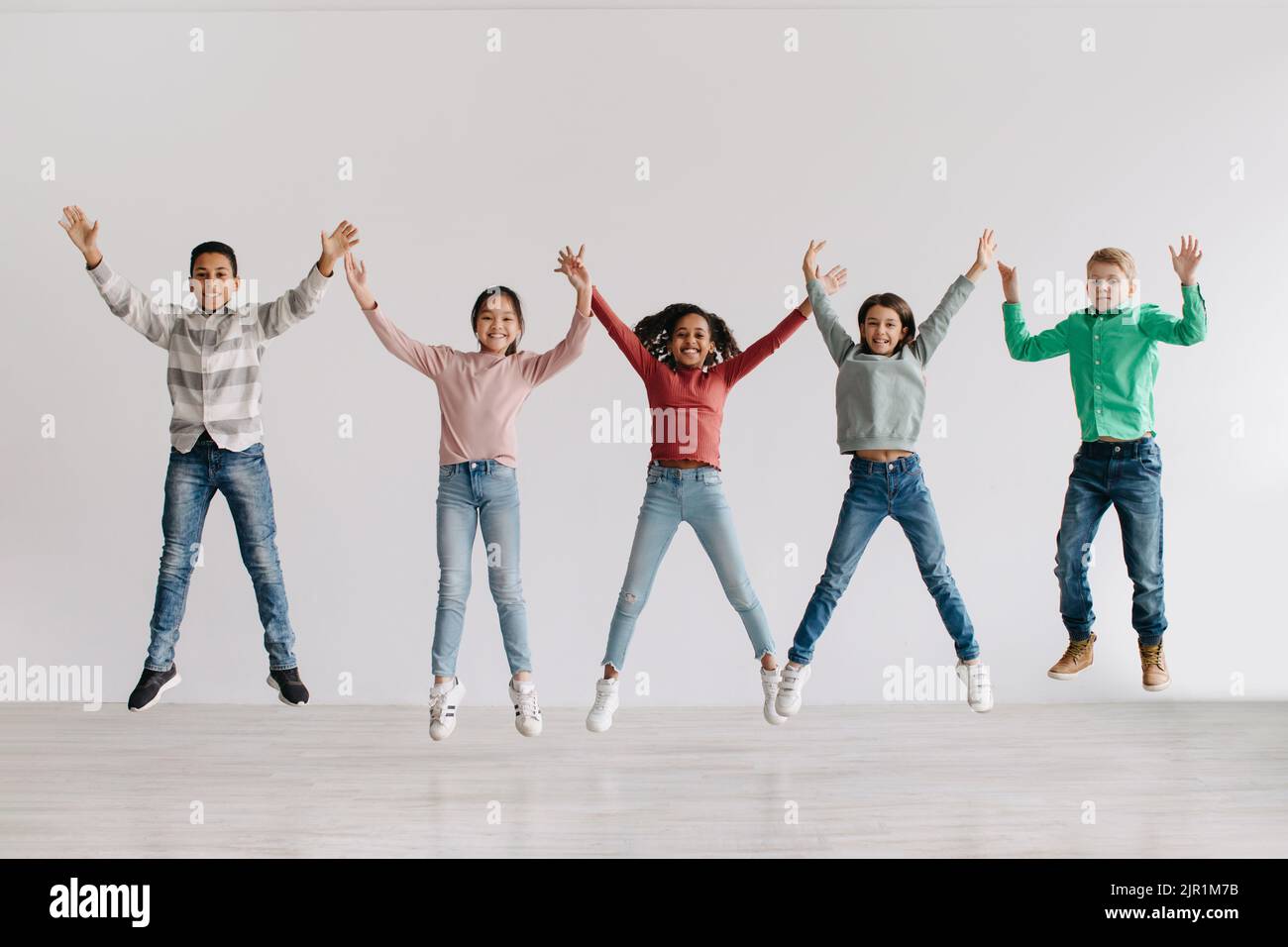 Eine Gruppe Von Fröhlichen, Vielfältigen Kindern, Die Im Freien Die Arme Hochheben Stockfoto