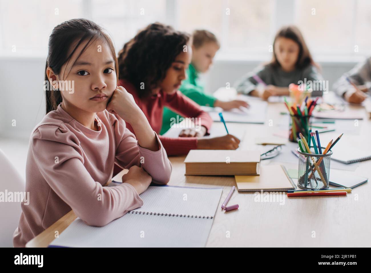 Traurig Asiatisch Schulmädchen Blick Auf Kamera Sitzen Im Modernen Klassenzimmer Stockfoto