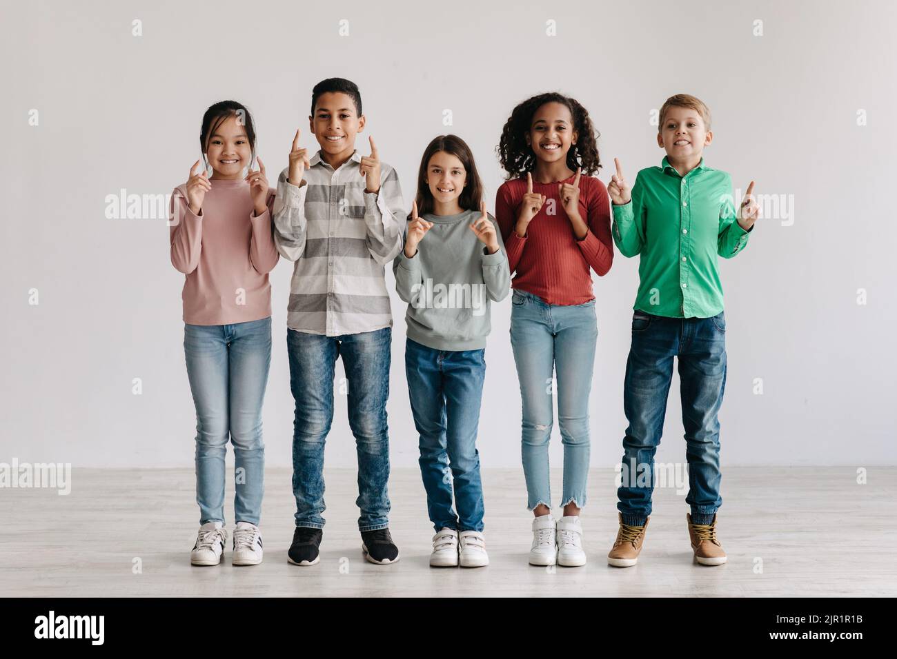 Fröhliche Multikulturelle Jugendliche Kinder Zeigen Die Finger Nach Oben Und Stehen Zusammen Im Freien Stockfoto