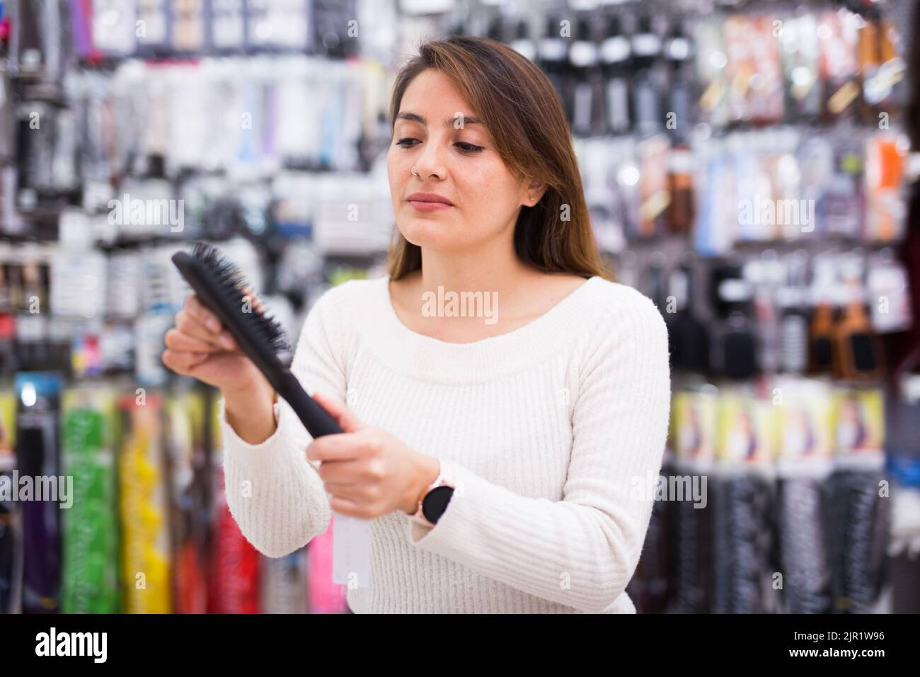 Positive junge Latina Wahl Haarbürste in Kosmetik-Shop Stockfoto