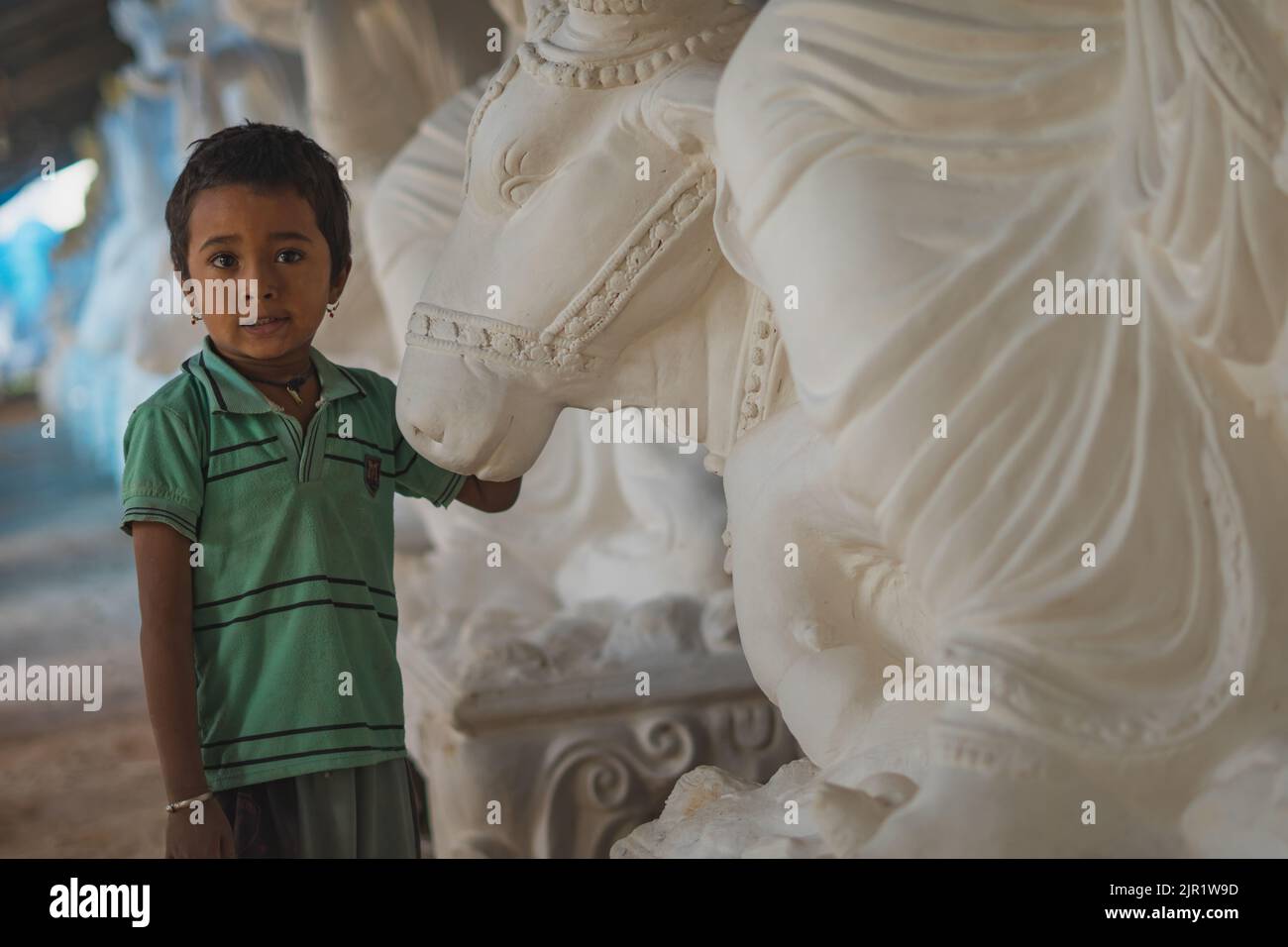 Pileru, Indien - 28,2022. Juli: Kind steht vor dem Stierkopf-Idol. Ohrringe an einem Jungen. Stockfoto