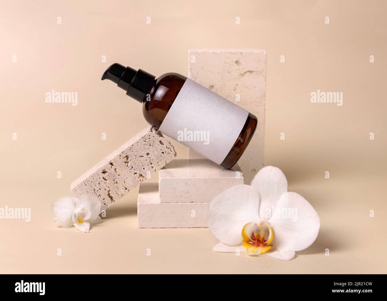 Dunkle Glasflasche aus einer Pumpe mit leerem Etikett in der Nähe von weißen Orchideenblumen und Steinen auf hellgelb, Nahaufnahme, Mockup. Hautpflege handgemachte Schönheit Stockfoto