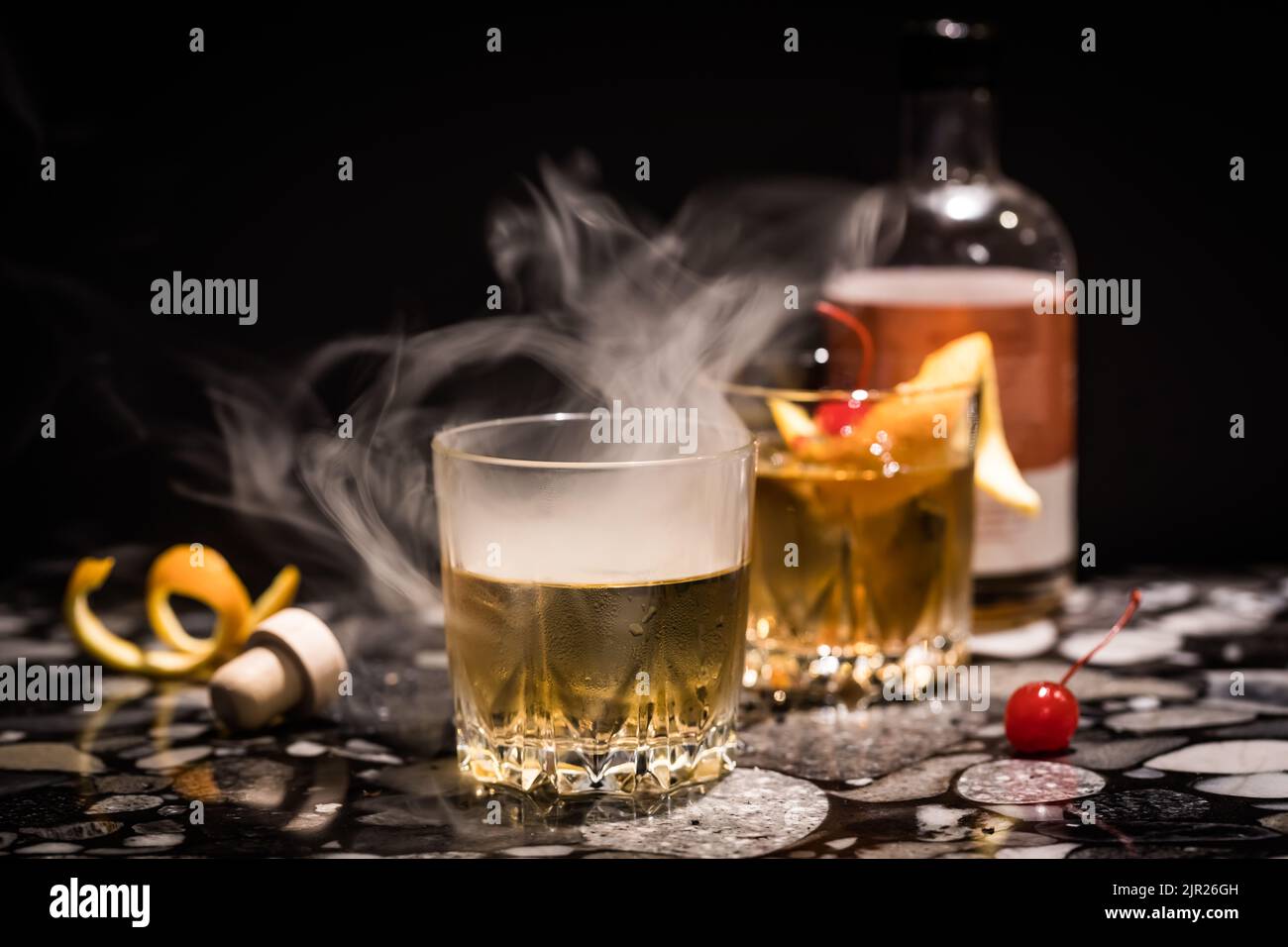 Rauch, der aus einem altmodischen Cocktail vor schwarzem Hintergrund aufwabt. Stockfoto
