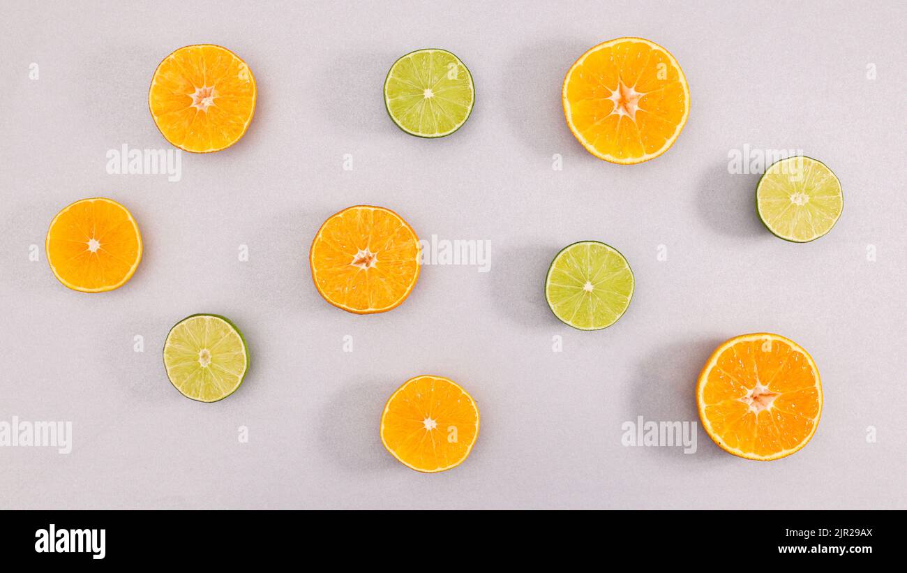 Kreative Sommerarrangements von Zitruslimen und Orangen auf grauem Hintergrund. Flach liegend Stockfoto