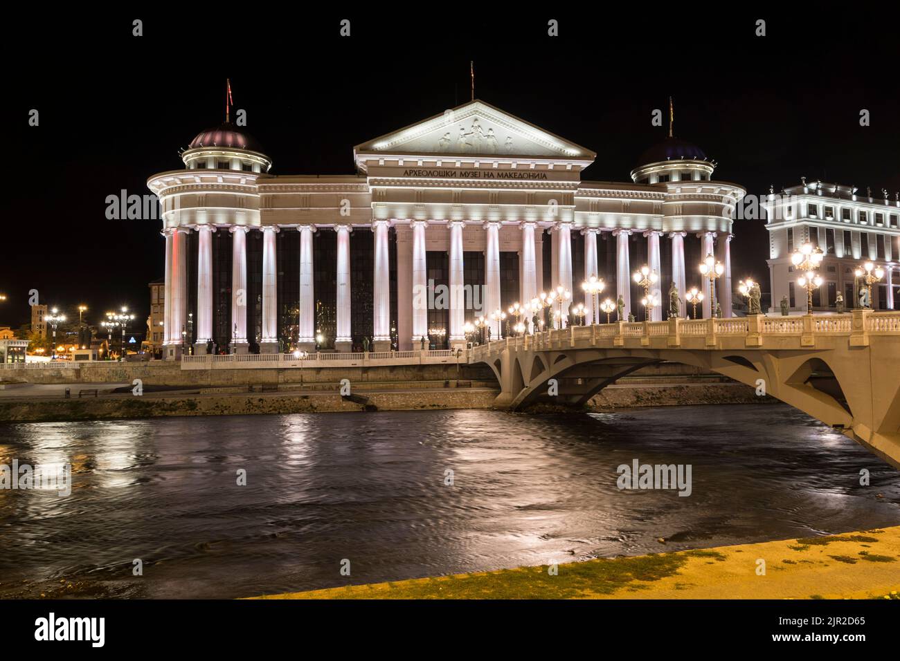 Beleuchtetes archäologisches Museum und Augenbrücke bei Nacht in Skopje, der Hauptstadt von Nord-Mazedonien. Stockfoto