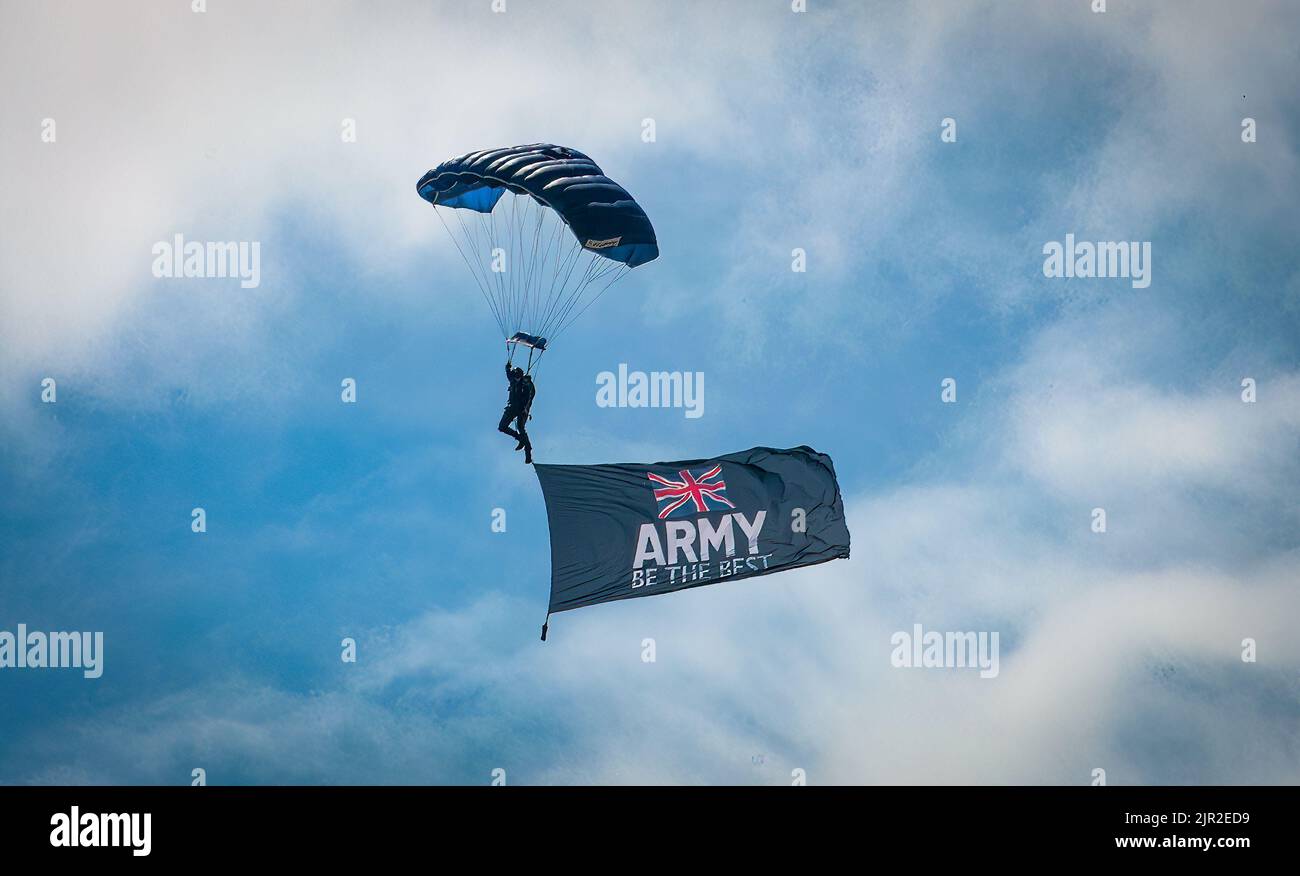 Ein Mitglied des Teams der Tigers Army Fallschirmabwehr zeigt eine Flagge mit der Aufschrift „Army Be the Best“, als er auf der jährlichen Eastbourne Airshow, ON, landet Stockfoto
