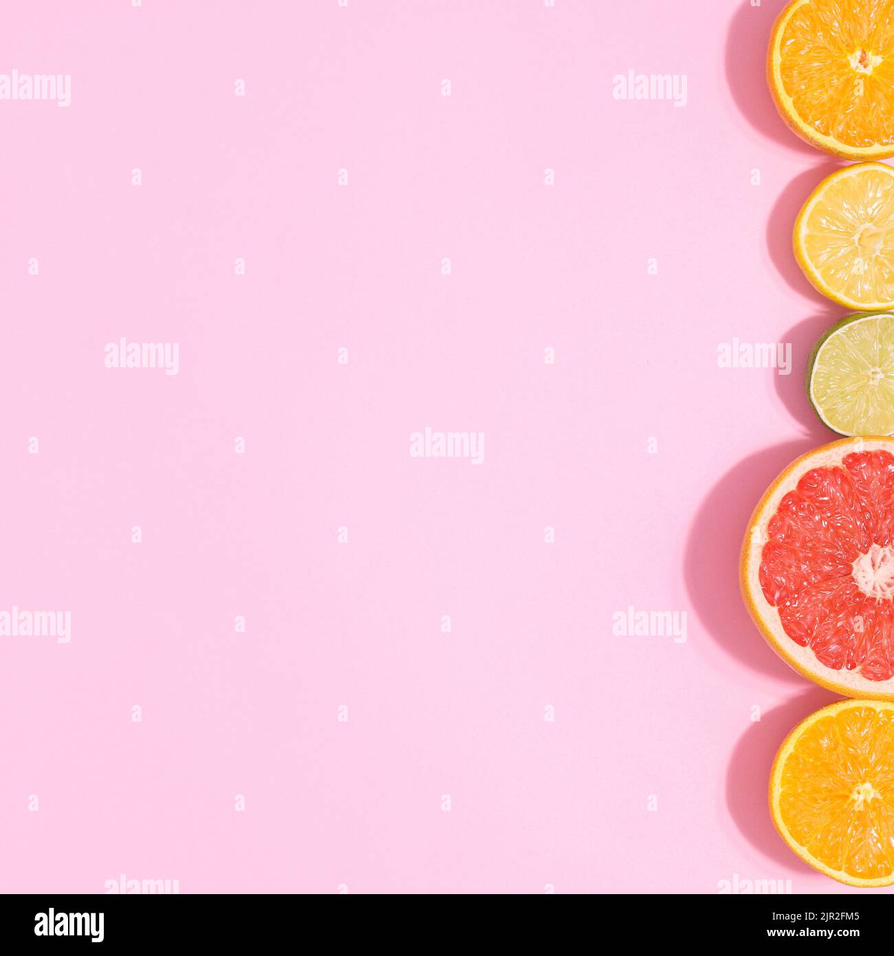 Pastellrosa Hintergrund mit geschnittenen Zitrusfrüchten auf der rechten Seite. Kopierraum flach lat. Sommerkonzept Stockfoto