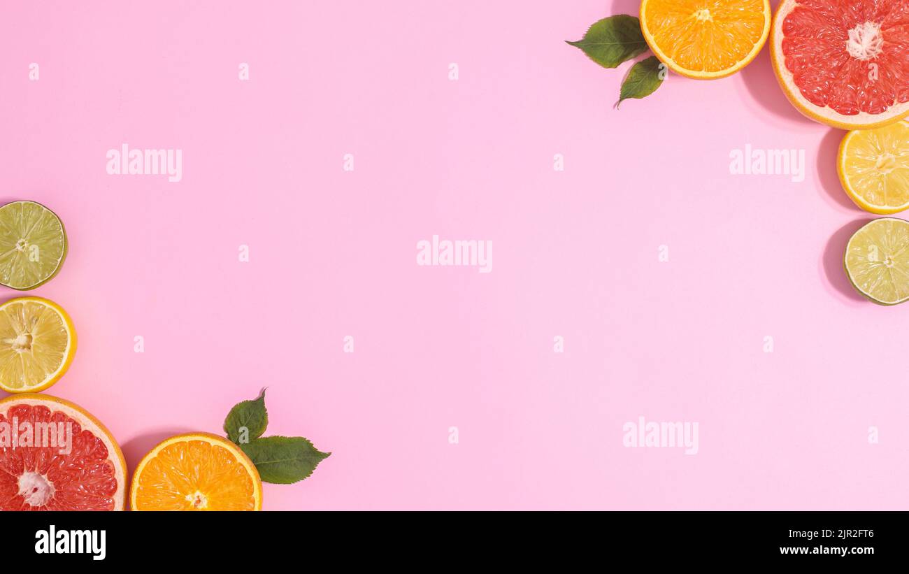 Pastellrosa Hintergrund mit in Scheiben geschnittenen Zitrusfrüchten in den Ecken. Kopierraum flach lat. Sommerkonzept Stockfoto